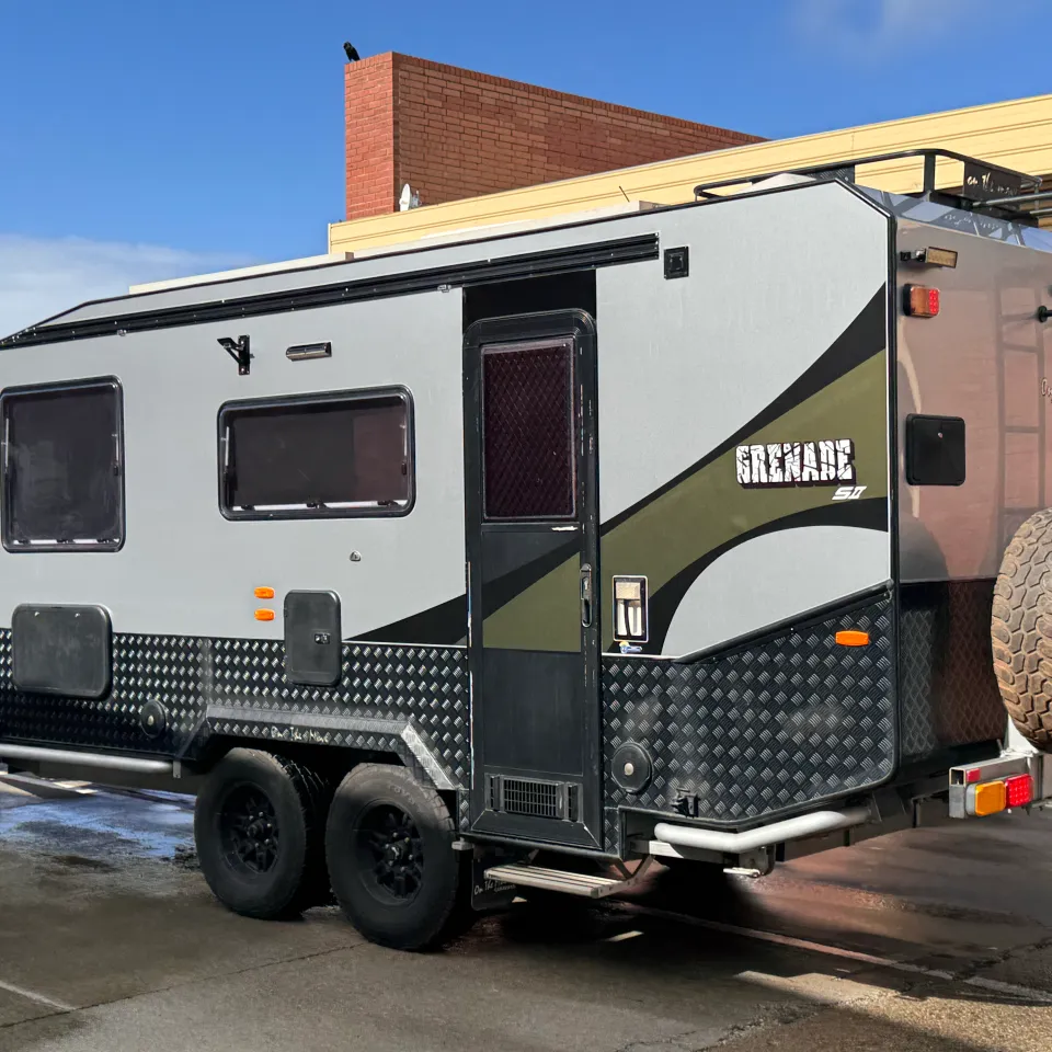 Silver and olive green caravan outside the workshop after its exterior refresh