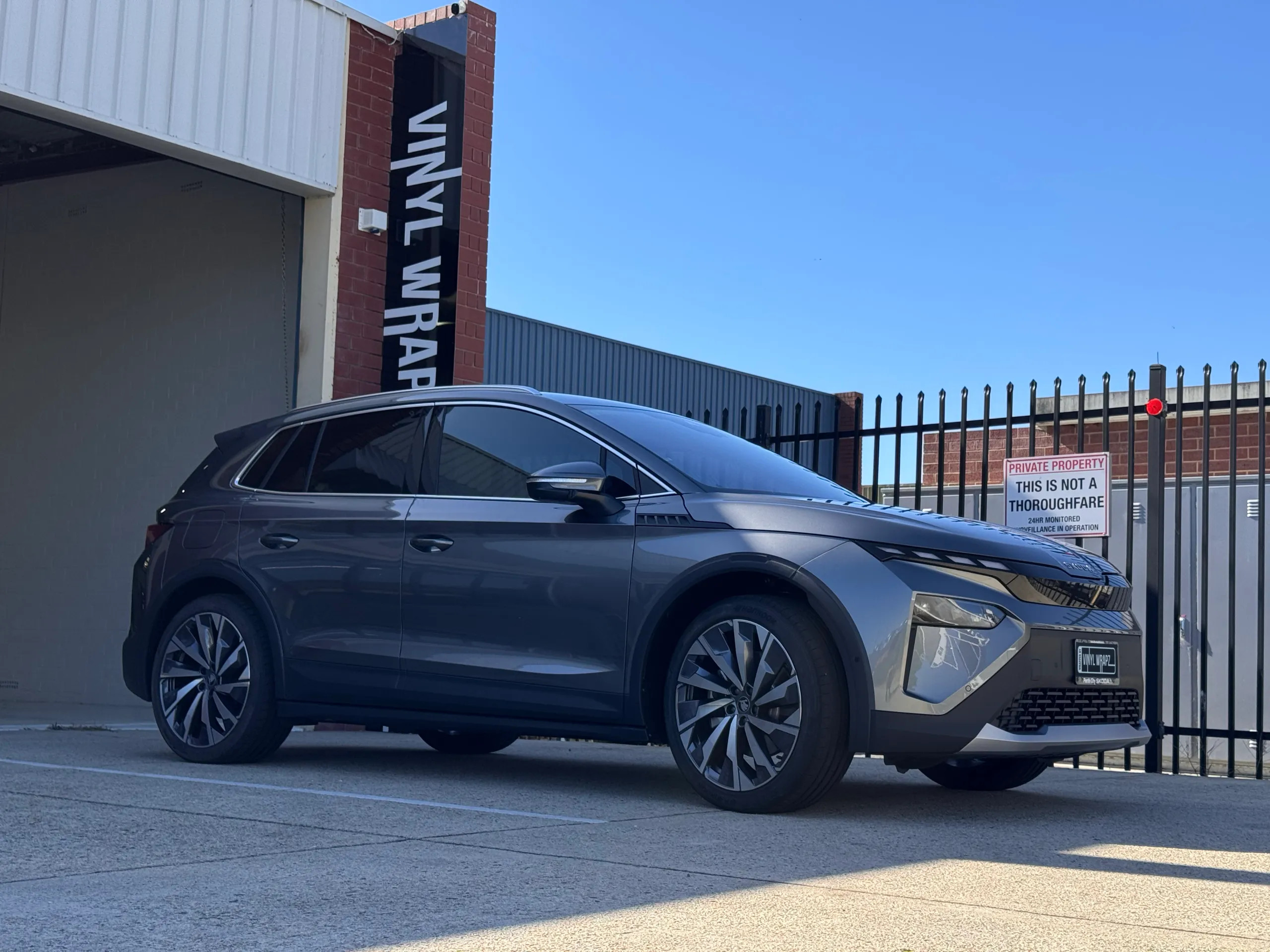 Grey Skoda Elroq parked outside the Vinyl Wrapz workshop, viewed from the front quarter