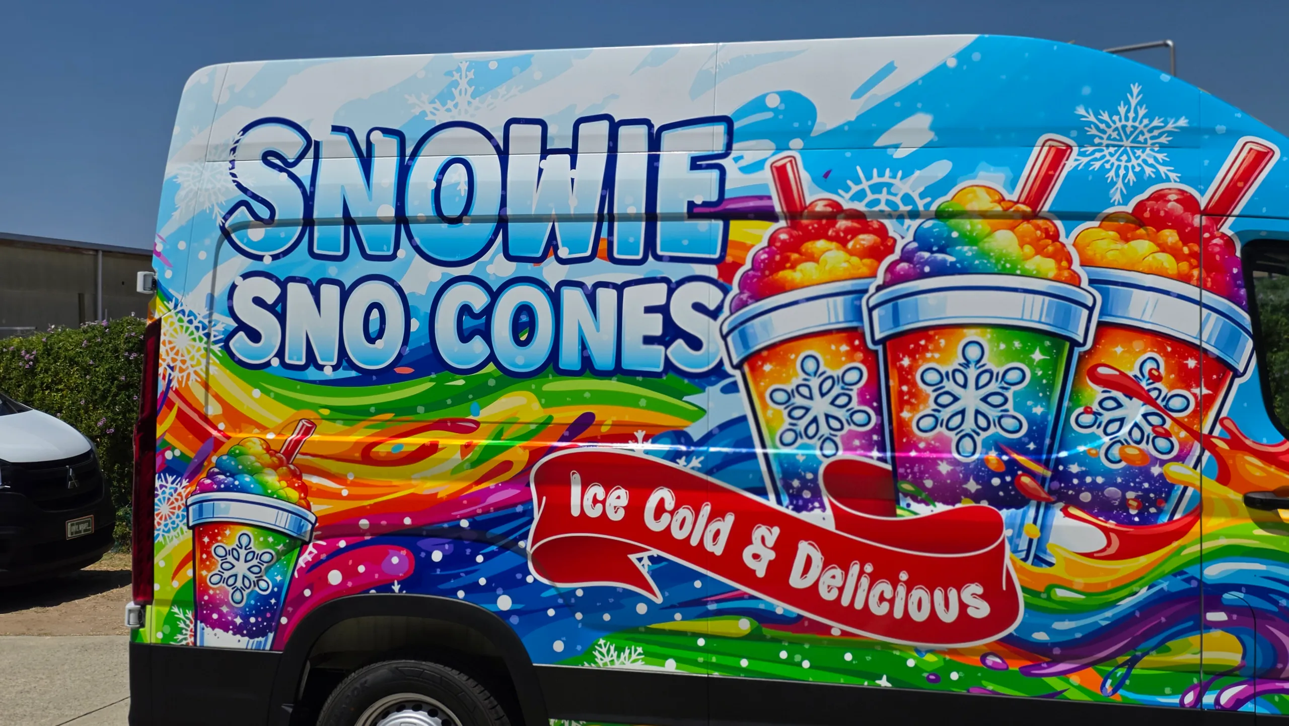Close-up of Snowie Sno Cones lettering and rainbow frozen-drink graphics on the van side