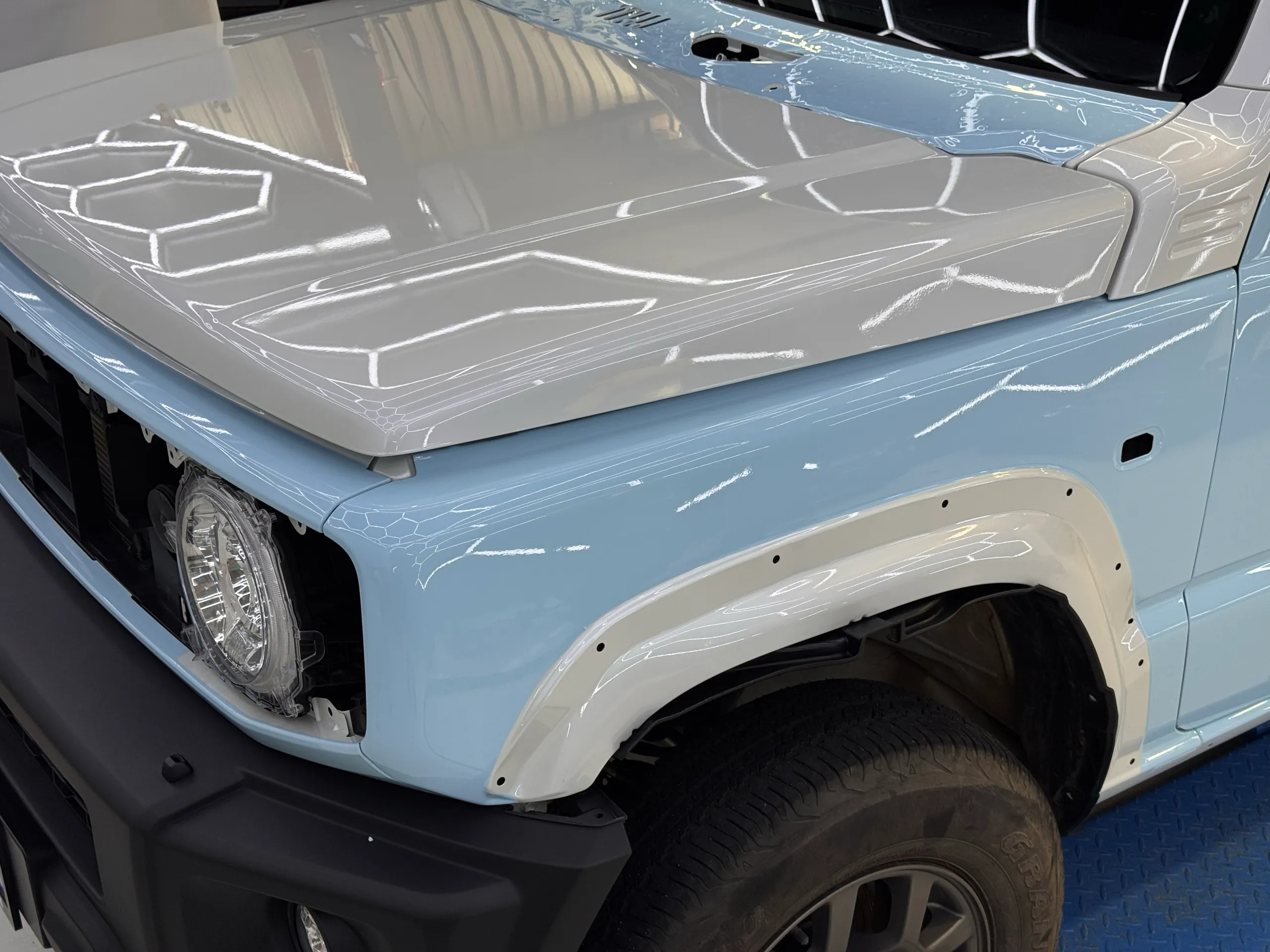 Light blue Suzuki Jimny front guard with wheel arch trim removed during installation