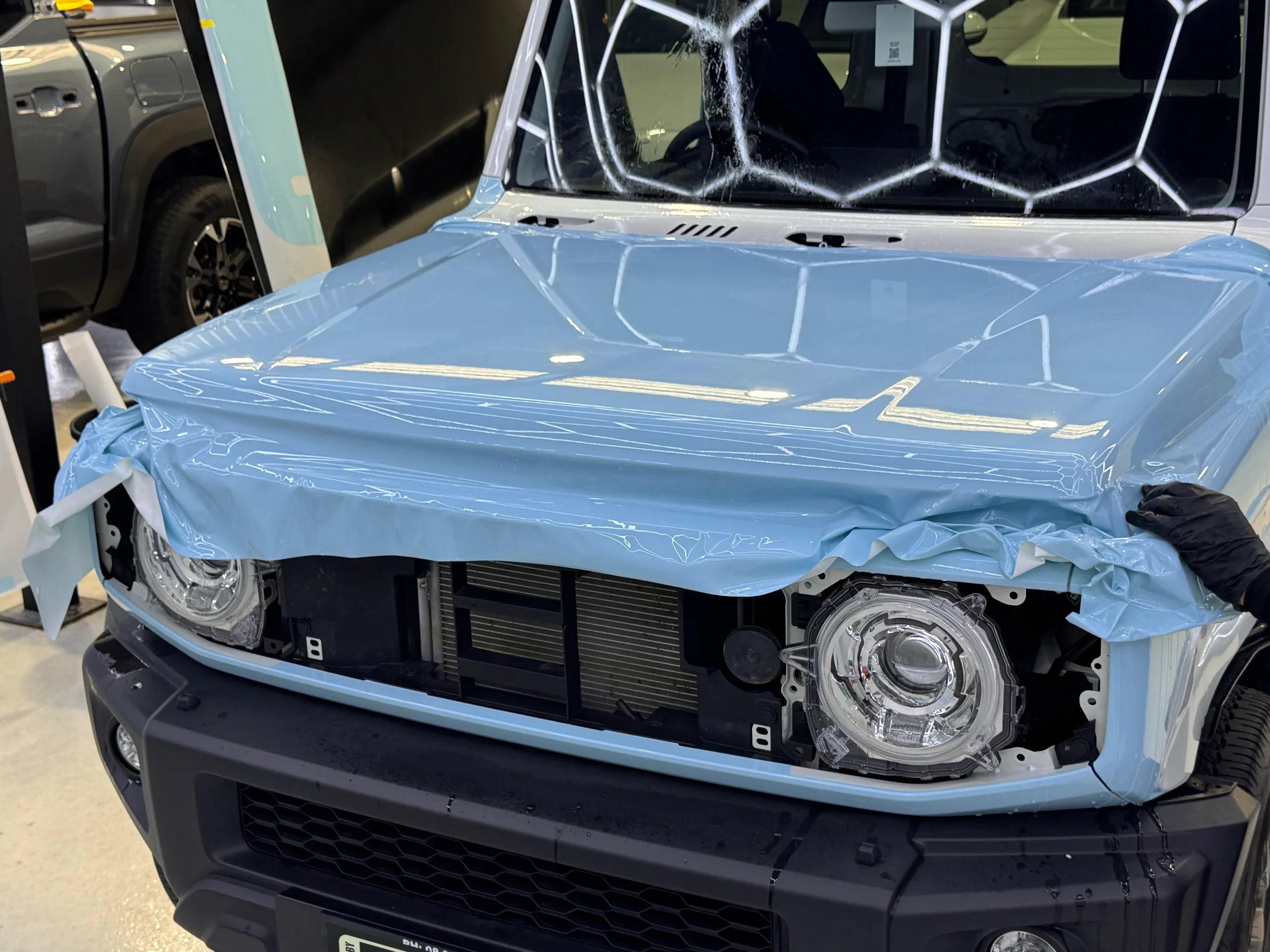 Light blue film stretched across the Suzuki Jimny bonnet, with excess film around the front edge