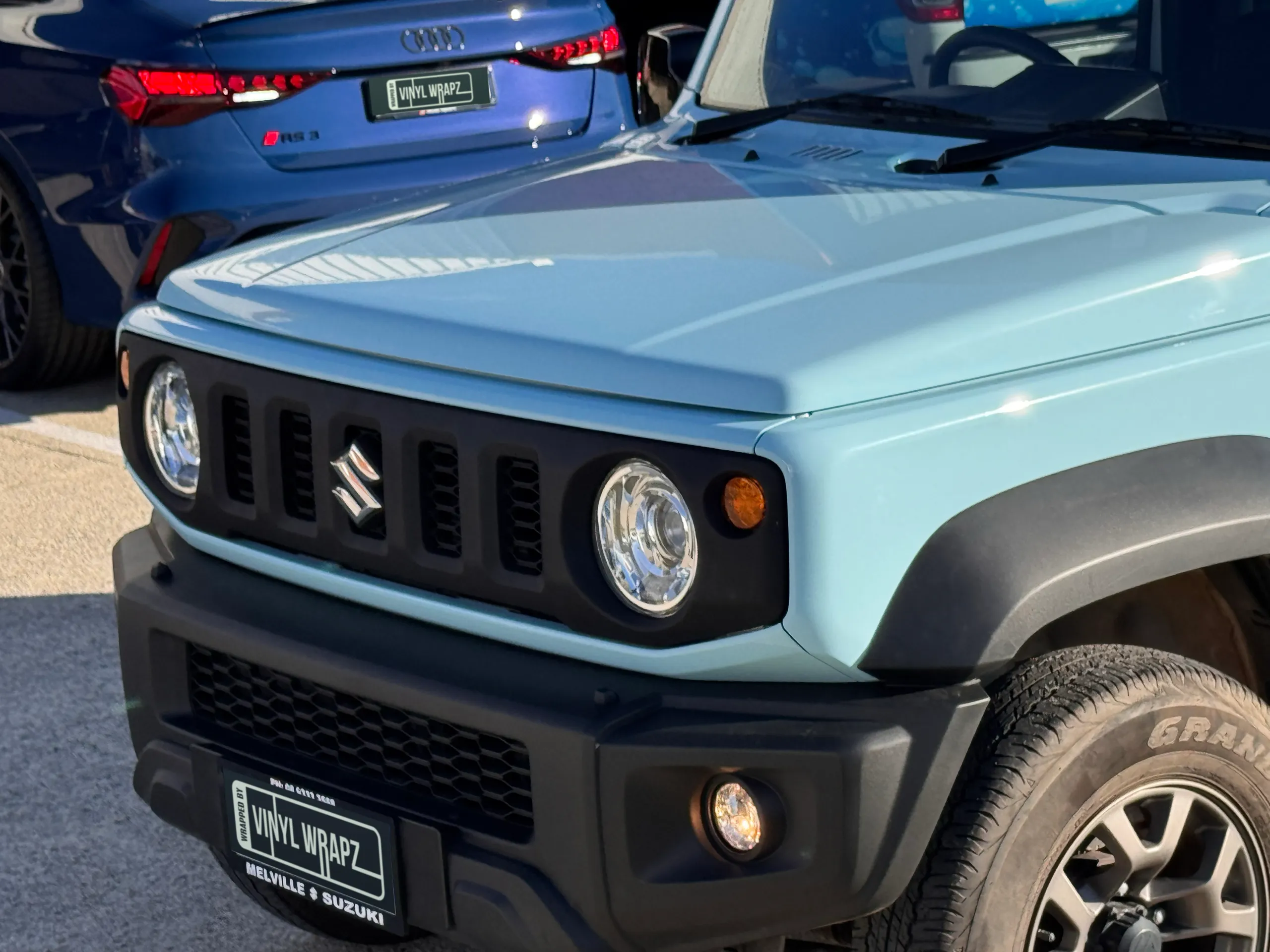 Light blue Suzuki Jimny bonnet, grille and headlight outside in sunlight