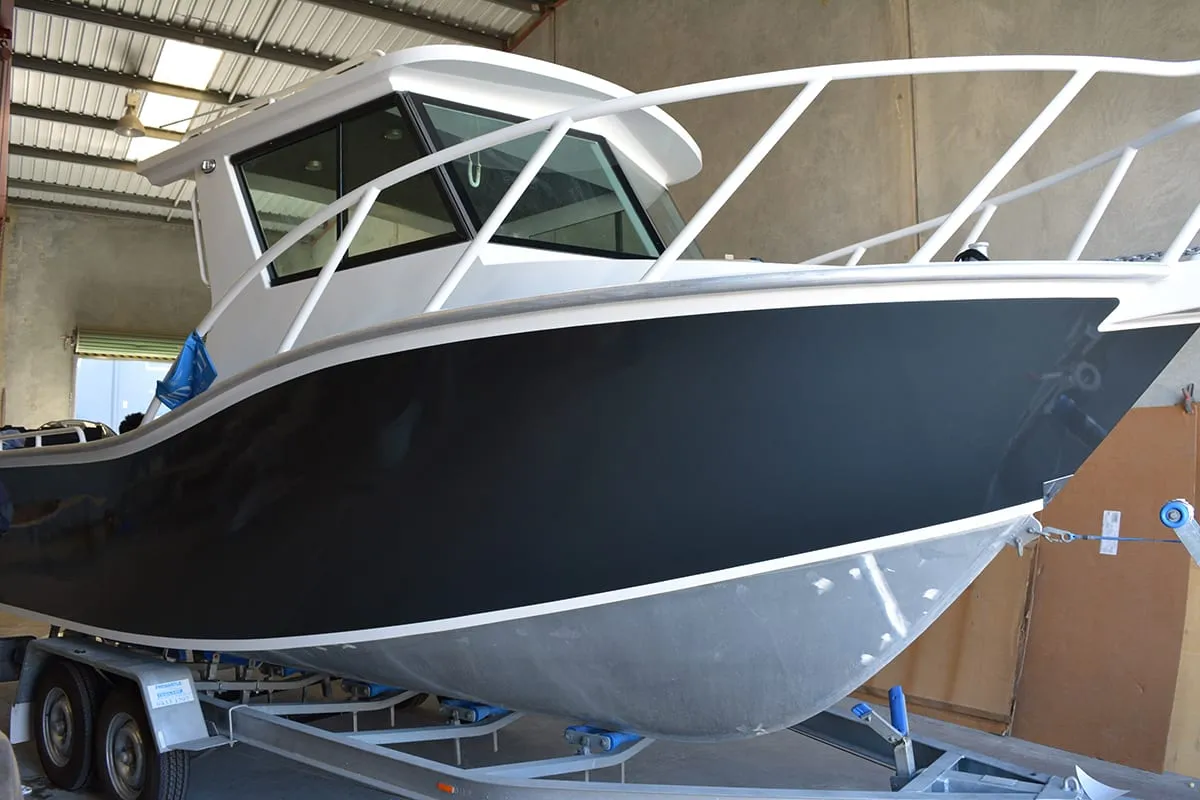7 m aluminium boat with its hull changed from green to a charcoal wrap, on its trailer in the workshop
