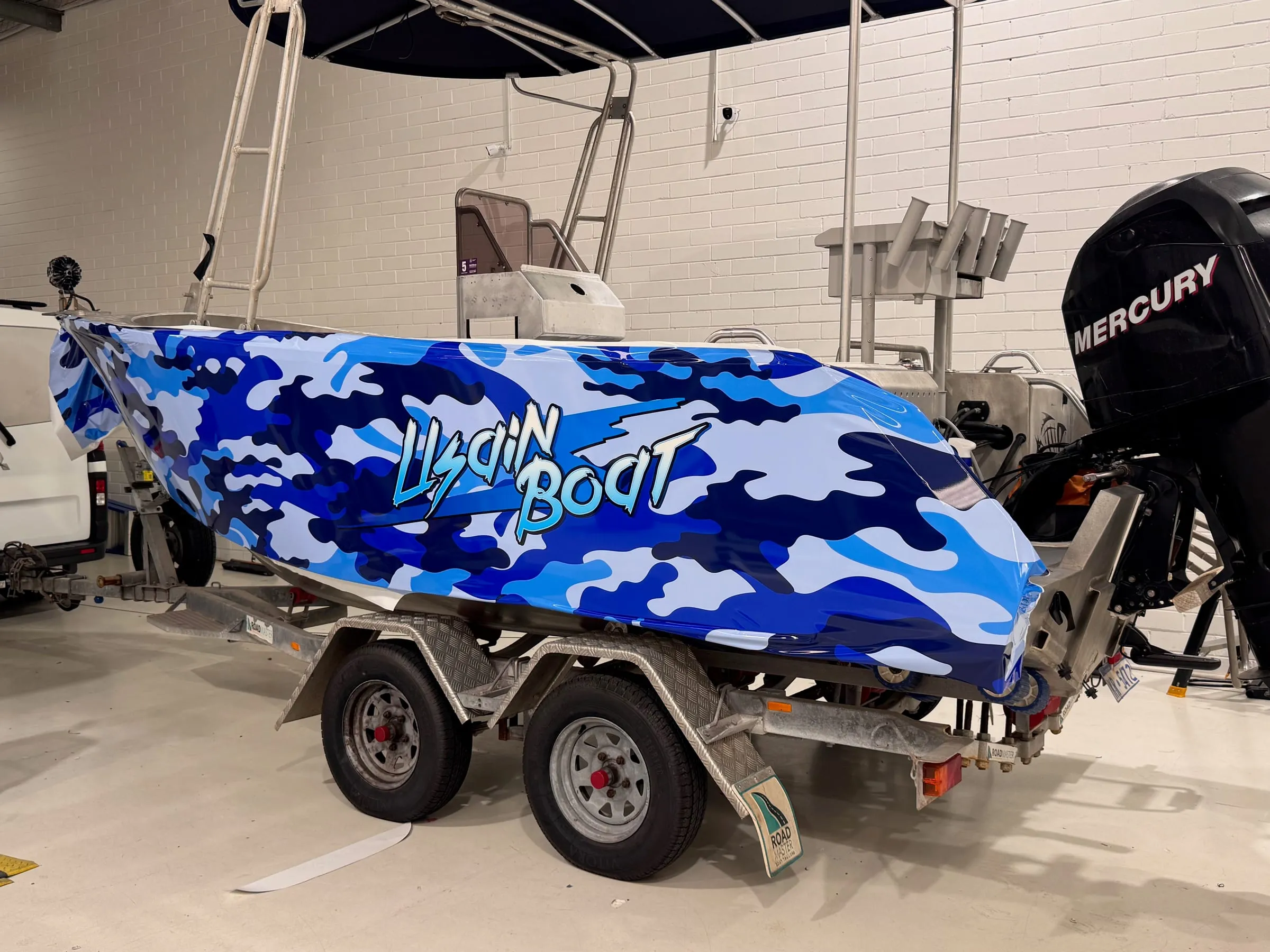 Aluminium boat in a blue camouflage printed wrap on its trailer in the Vinyl Wrapz workshop