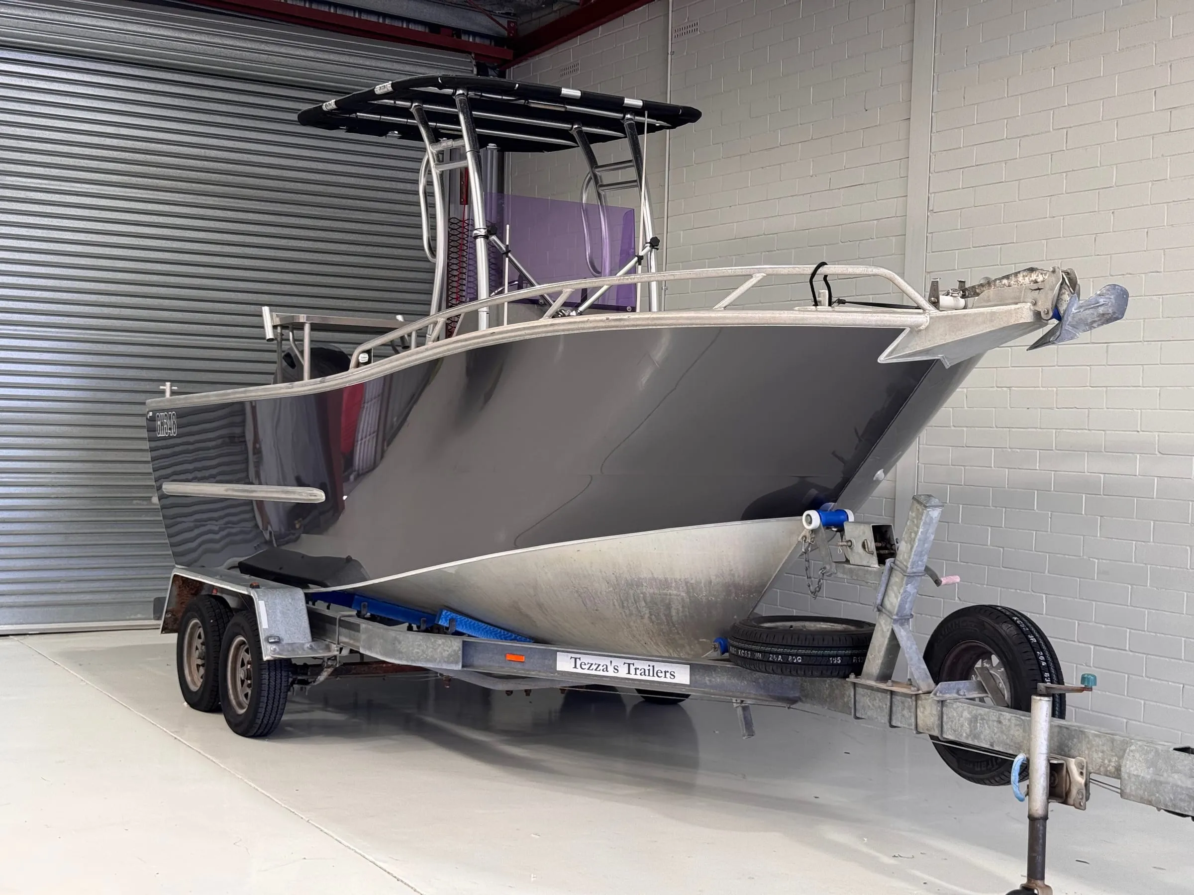 Aluminium centre-console fishing boat in a gloss dark grey hull wrap on its trailer in the Vinyl Wrapz workshop, Osborne Park