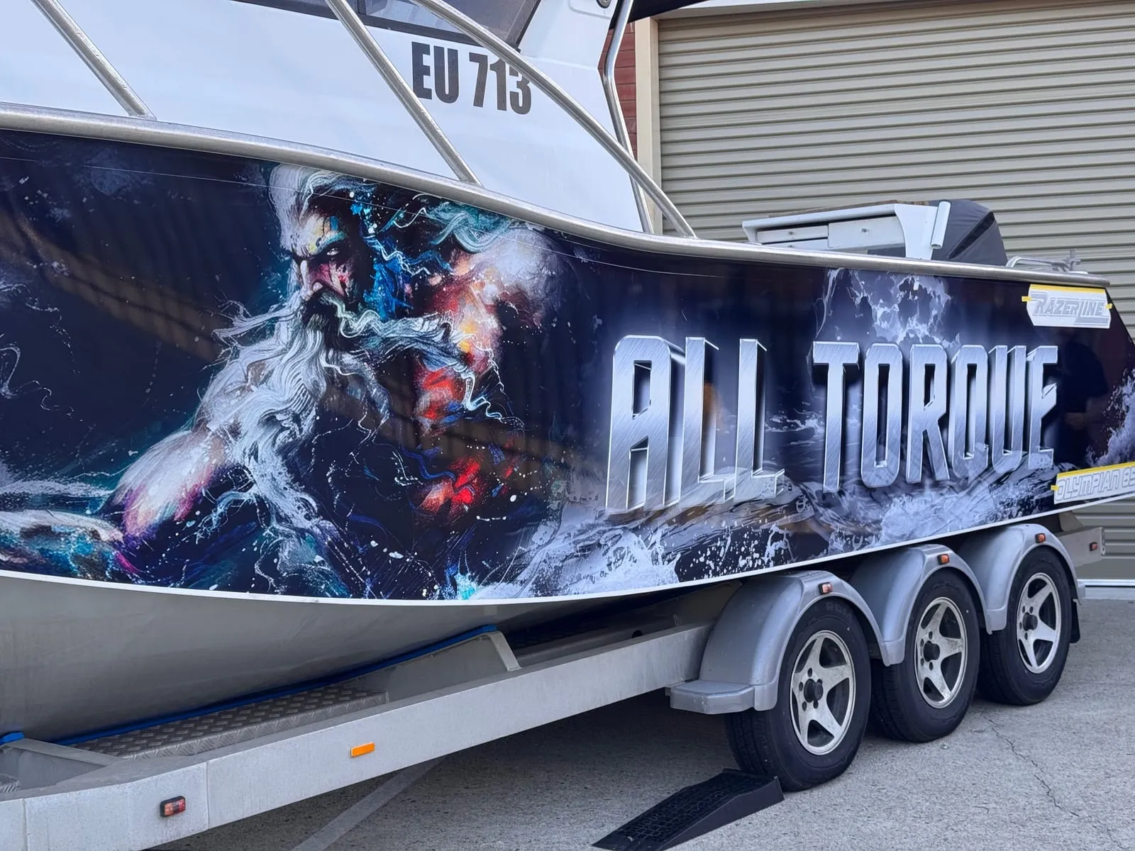 Custom printed Poseidon artwork and lettering on a cabin cruiser hull wrap outside the workshop