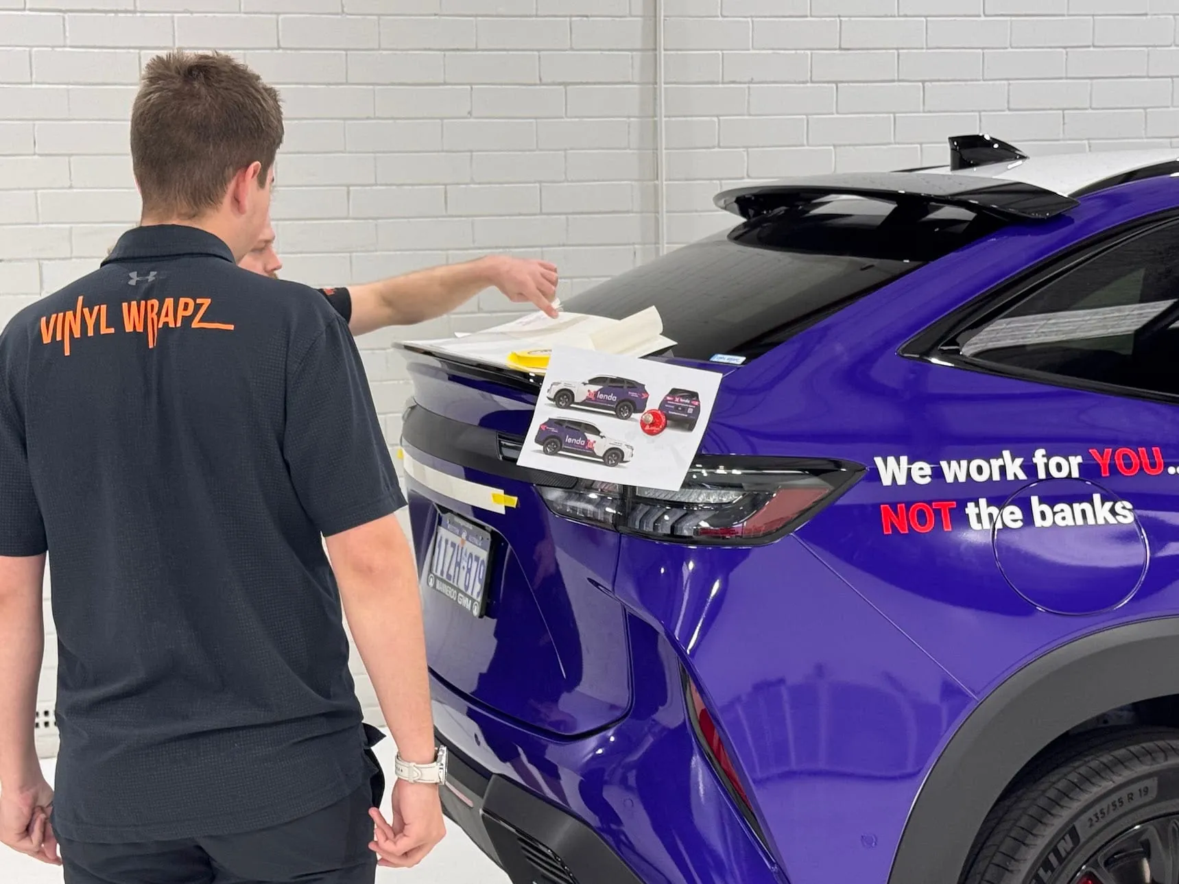 Vinyl Wrapz installers checking a freshly branded SUV against the printed proof in the workshop