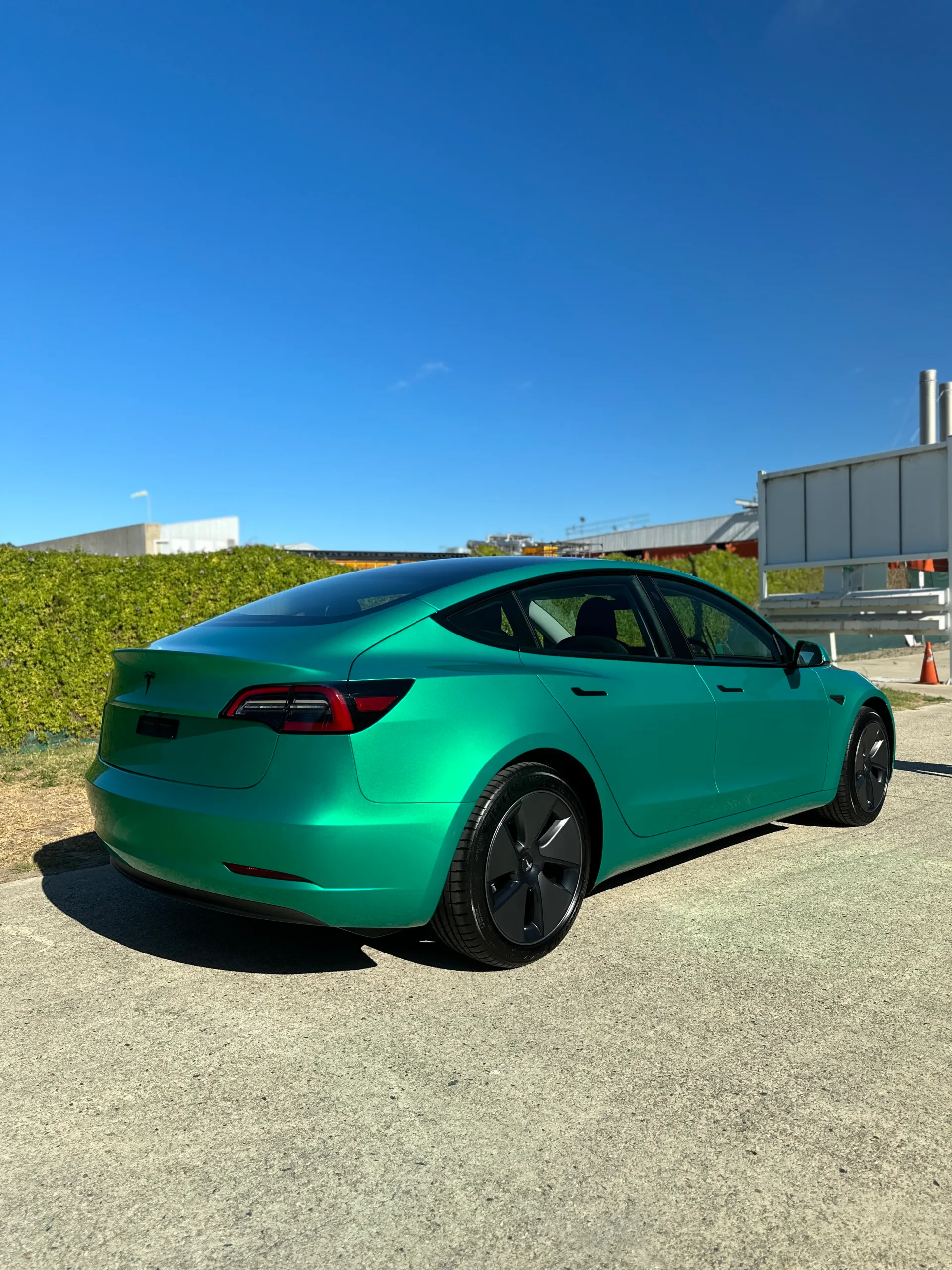 Envious green Tesla Model 3, rear quarter