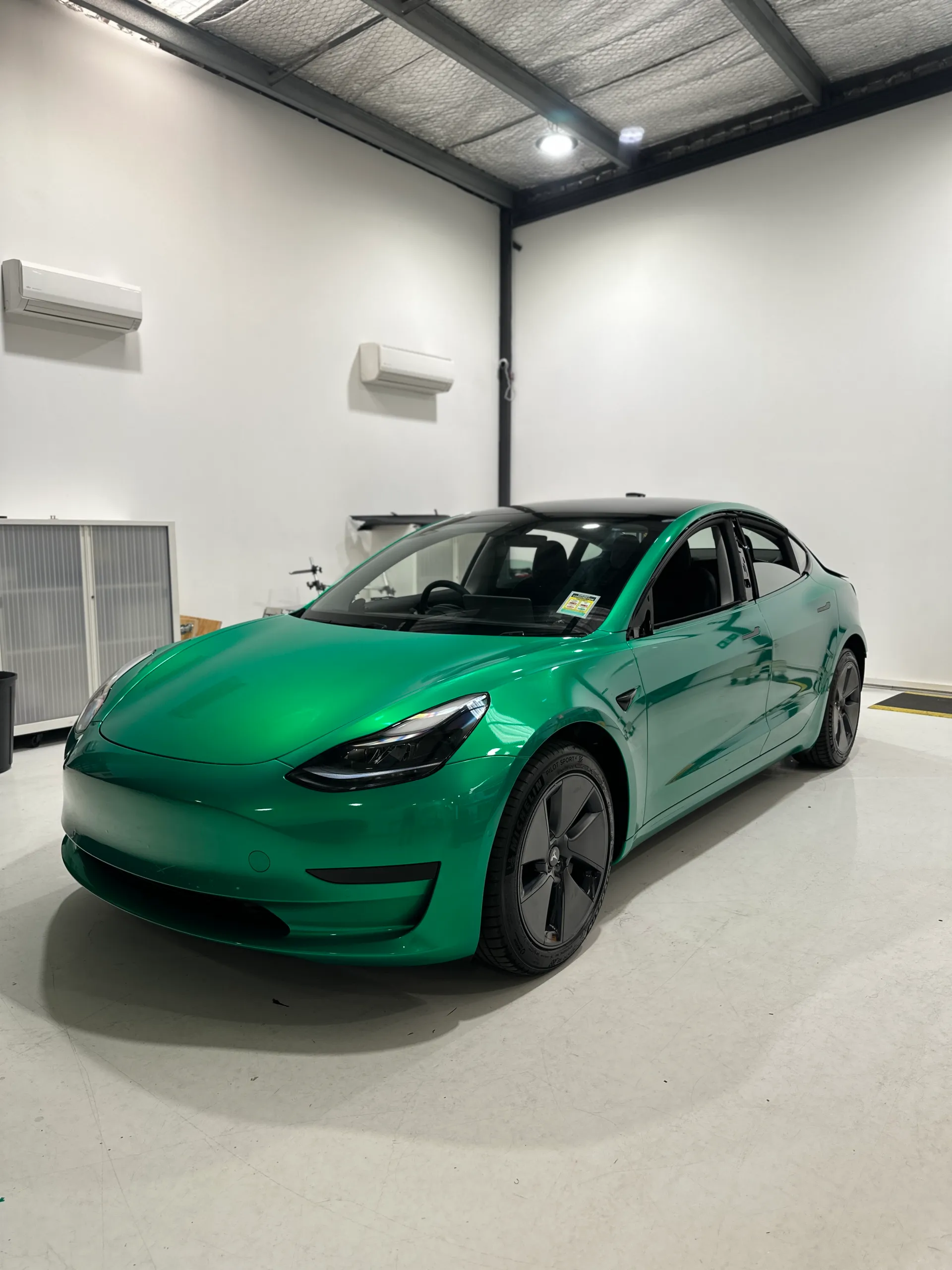 Envious green Tesla Model 3, front quarter