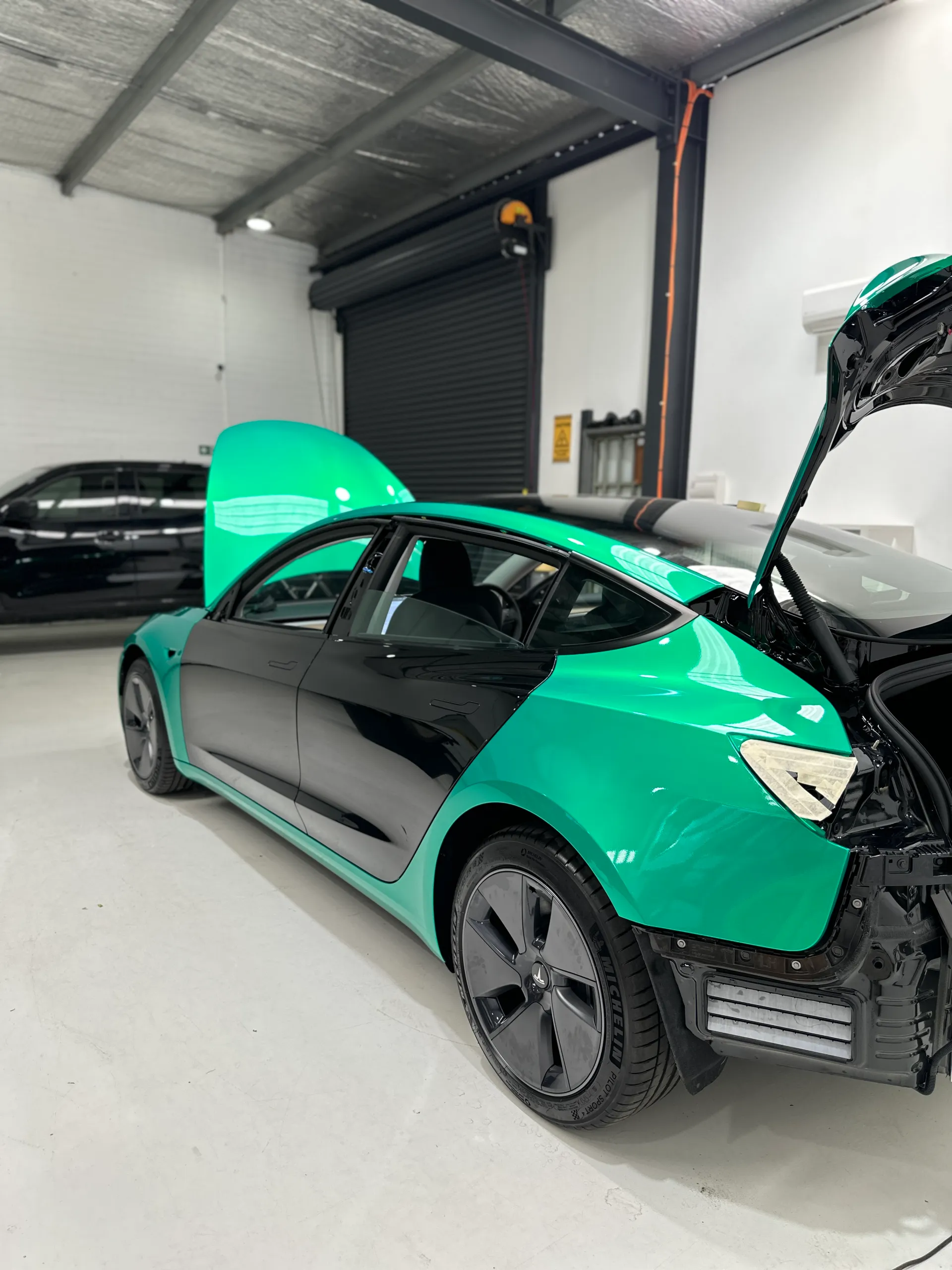 Envious green Tesla Model 3, rear quarter