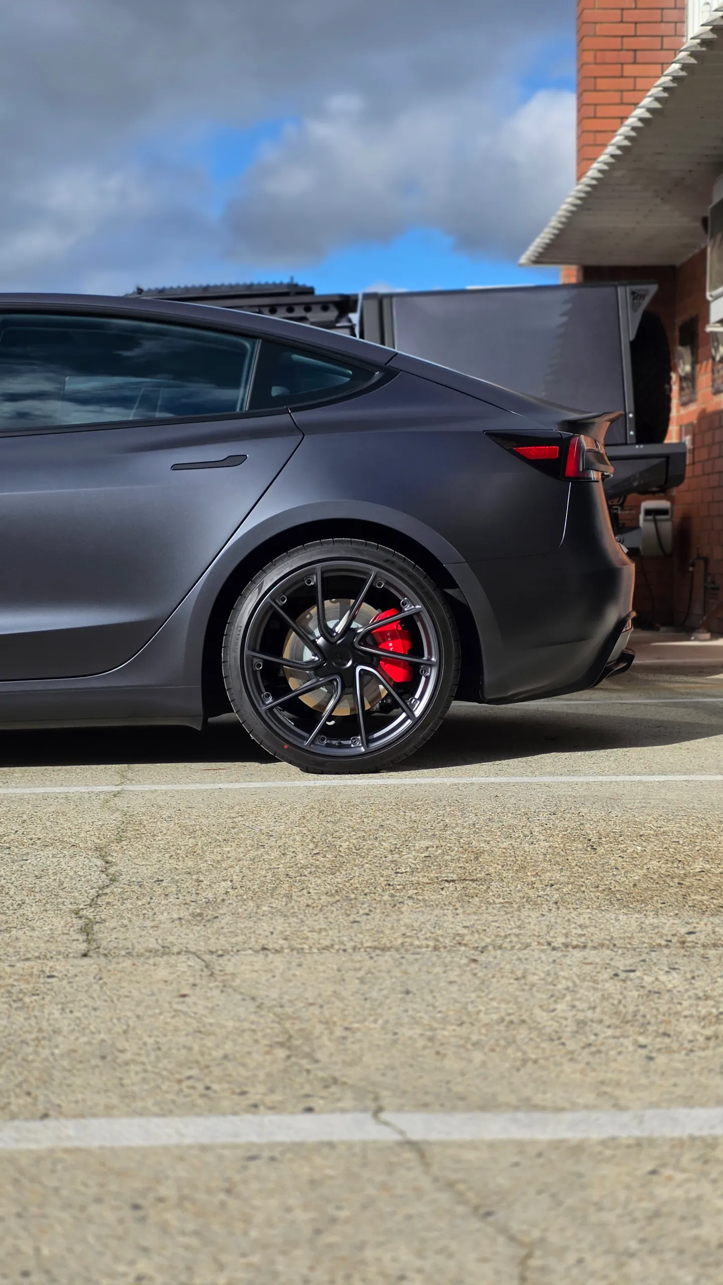 Satin grey Tesla Model 3 rear quarter and wheel with a red brake caliper