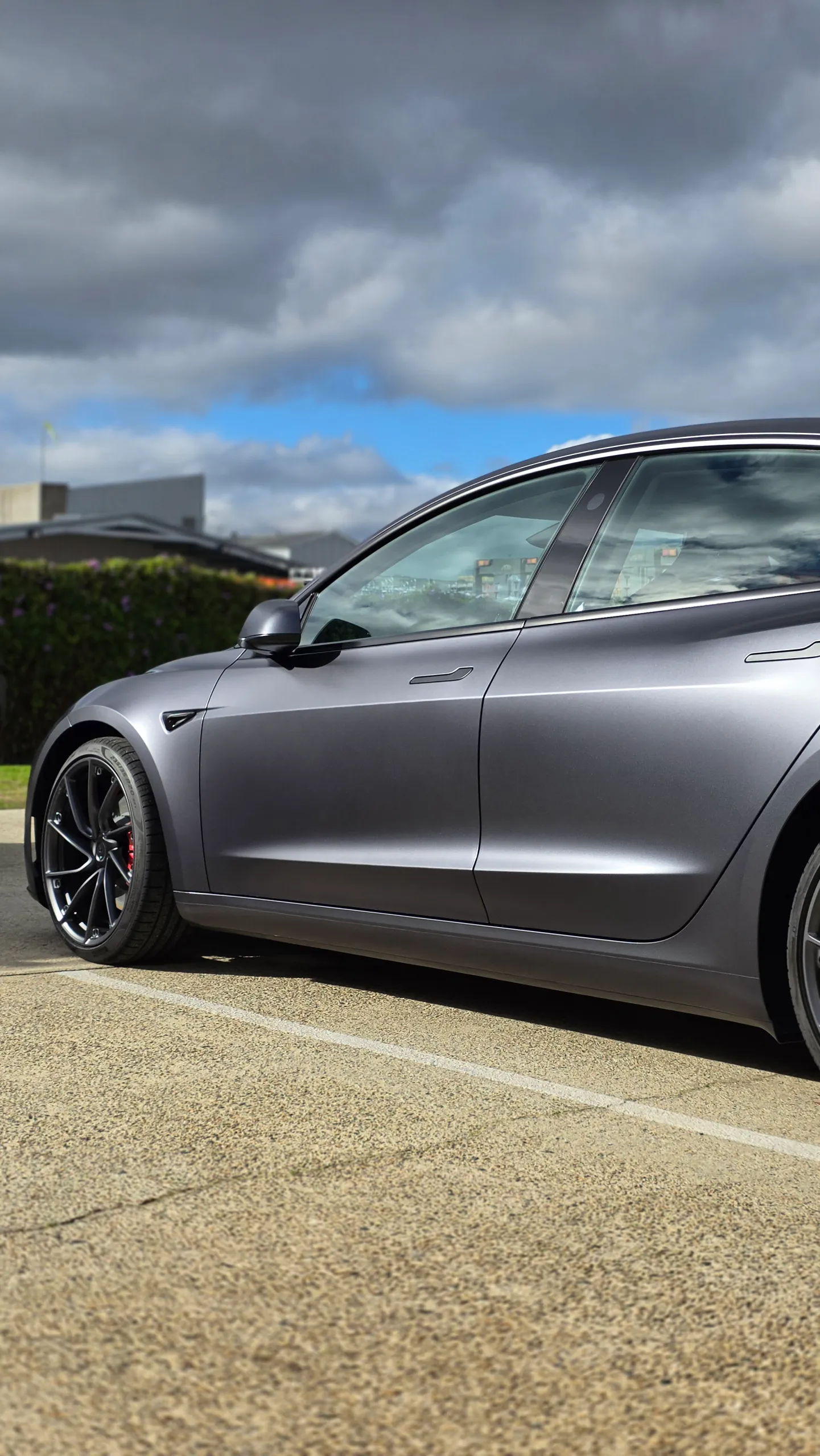 Satin grey Tesla Model 3 doors and front wheel outside the workshop