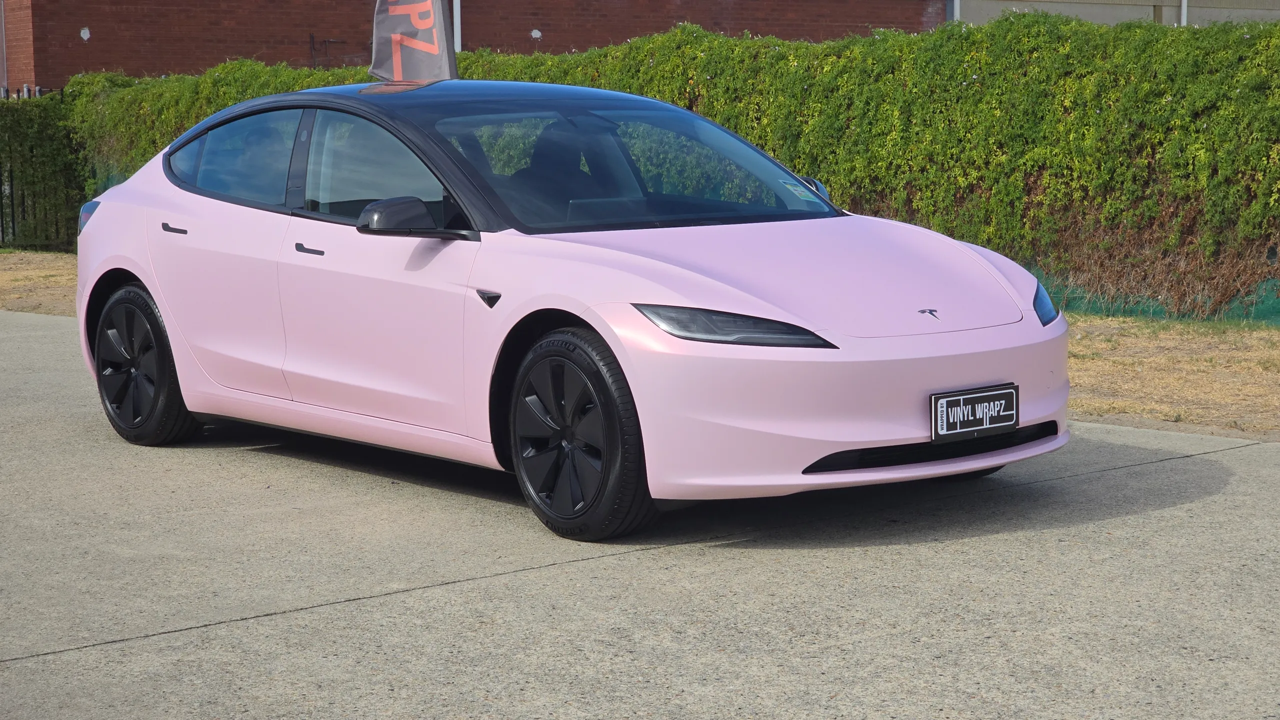 Pale pink satin Tesla Model 3 with black roof and wheels, front quarter