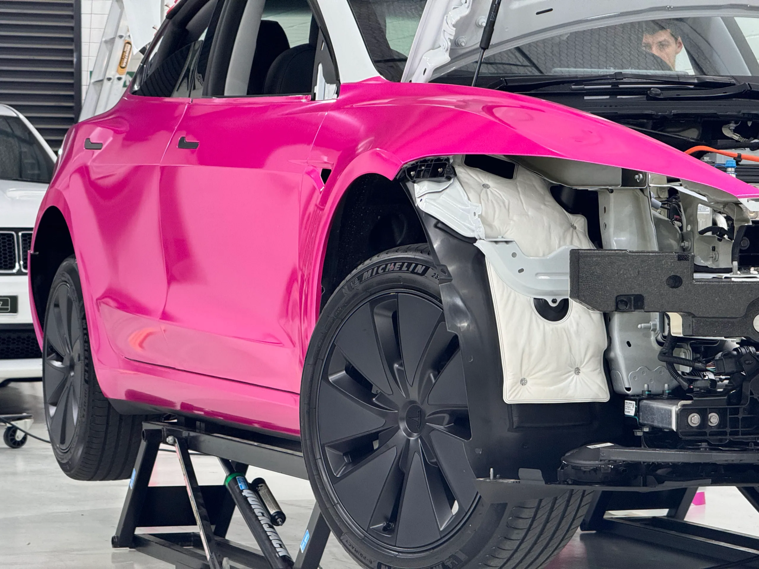 Pink Tesla Model 3 during installation with its front bumper and headlight removed
