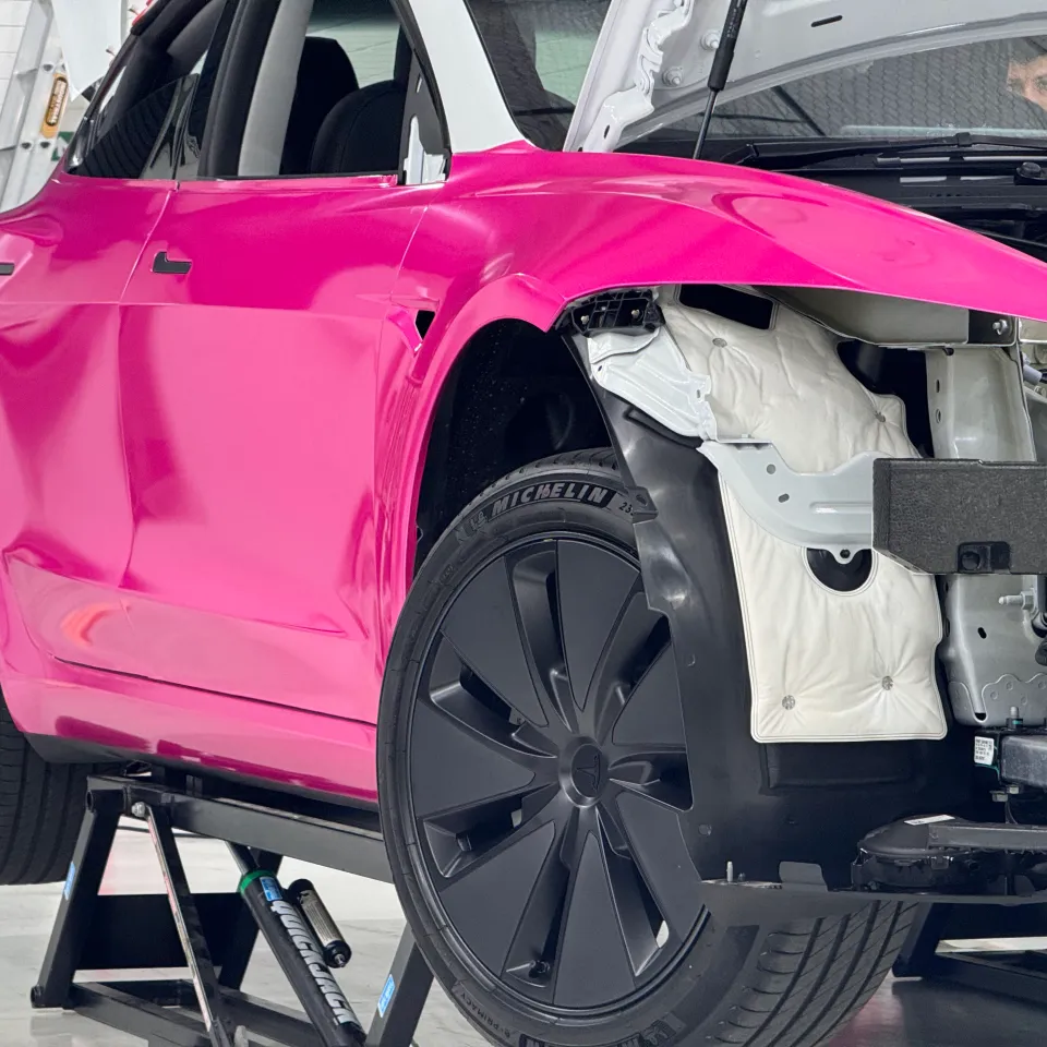 Pink Tesla Model 3 during installation with its front bumper and headlight removed