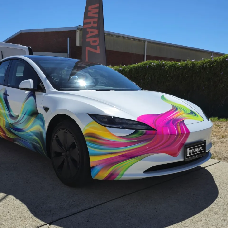 Tesla Model 3 with colourful splash graphics parked outside