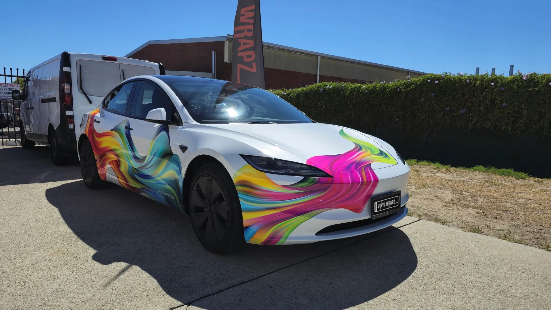 Tesla Model 3 with colourful splash graphics parked outside