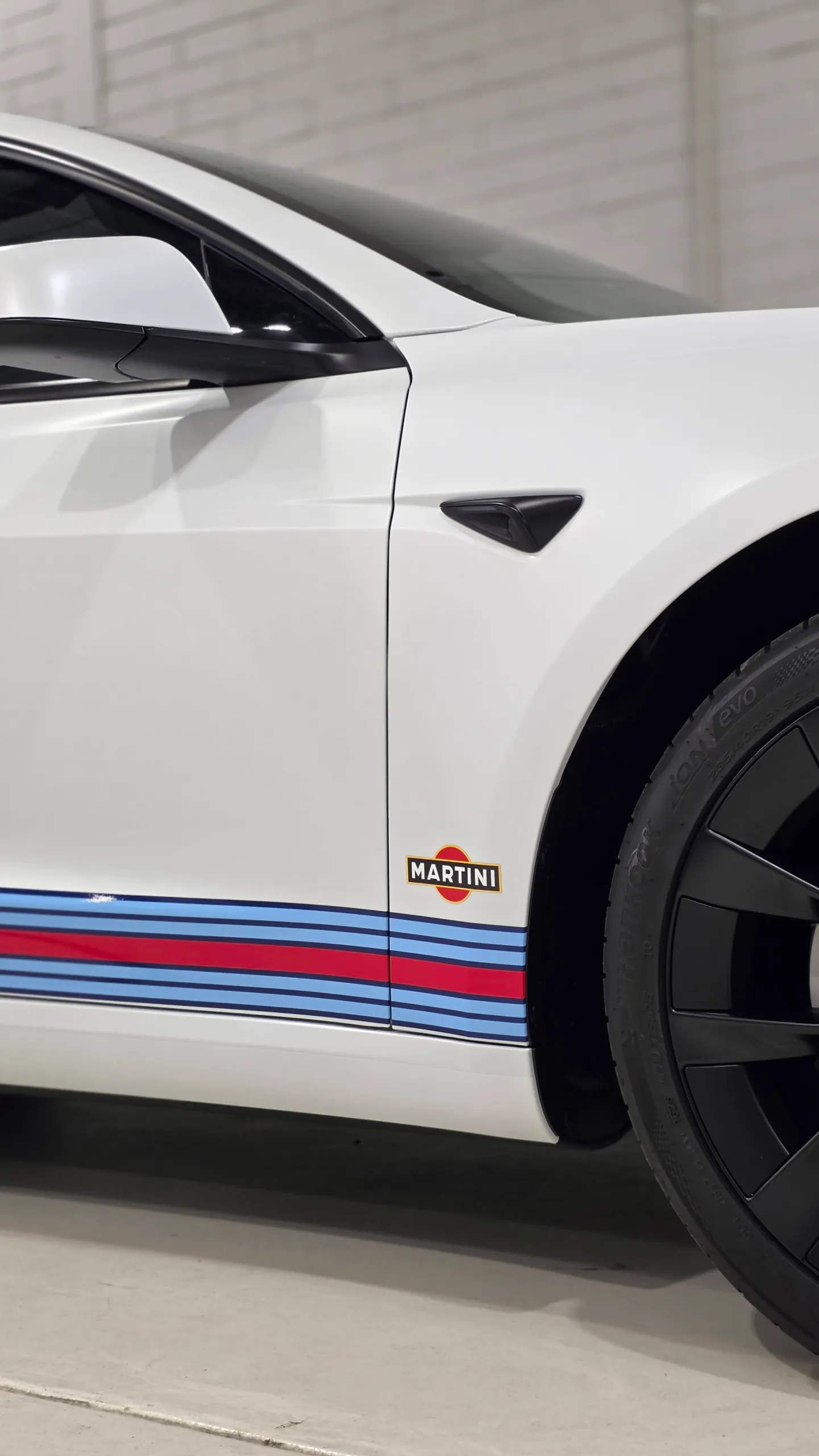 White Tesla front door and guard above red and blue Martini sill graphics