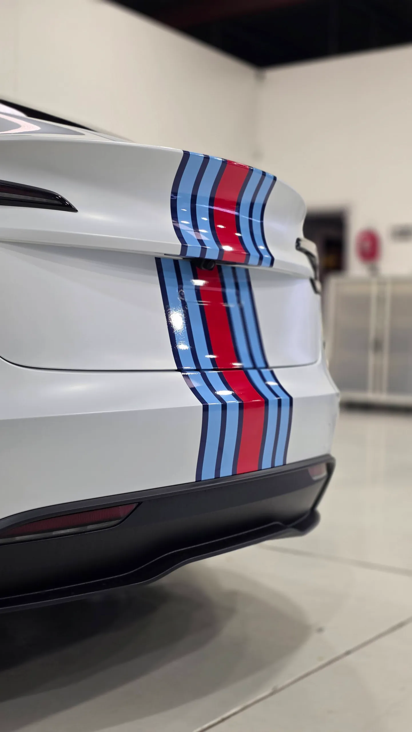 Red and blue stripes across the white Tesla boot and rear bumper