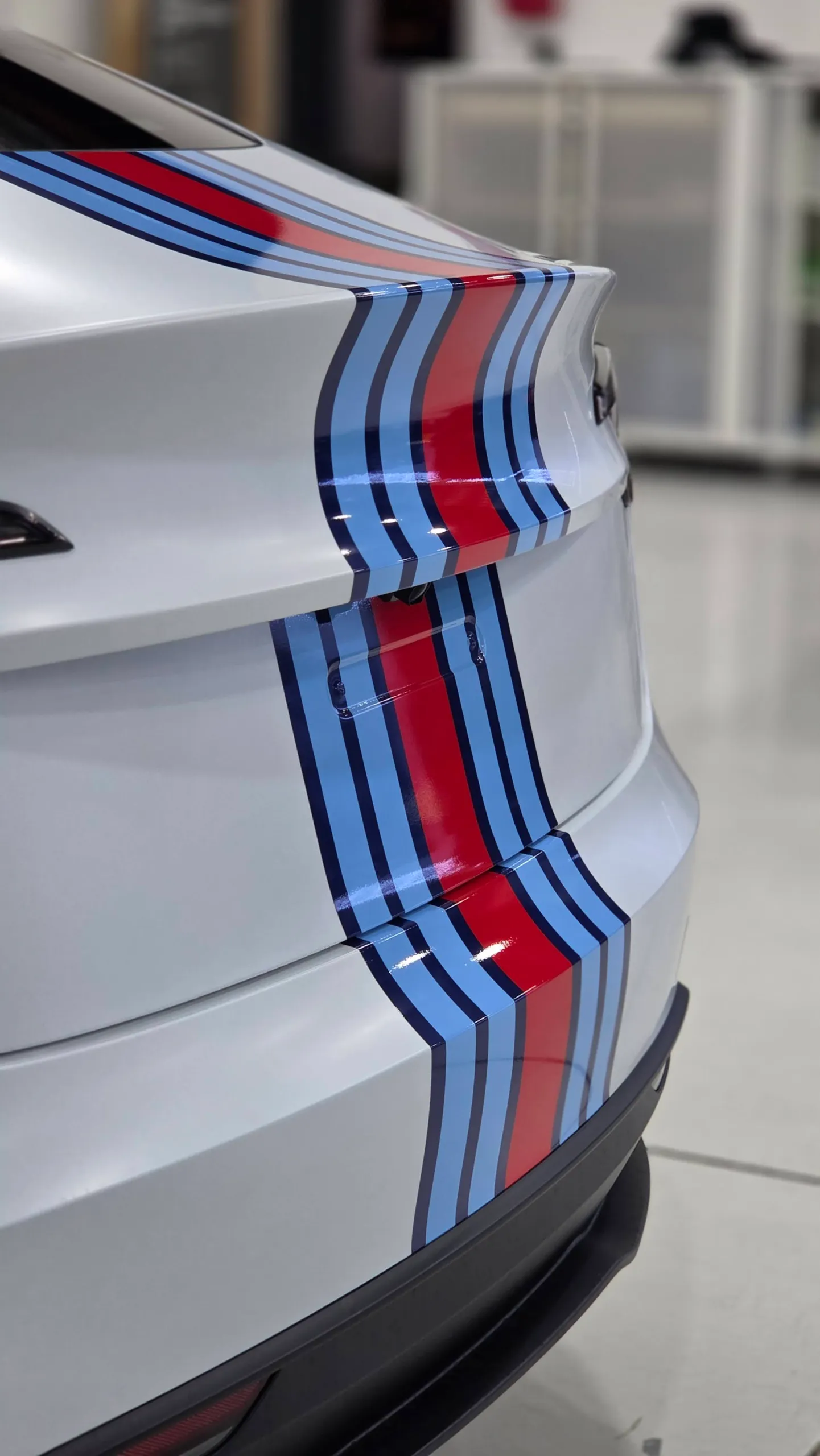 Close view of red and blue Martini stripes on the white Tesla rear bodywork