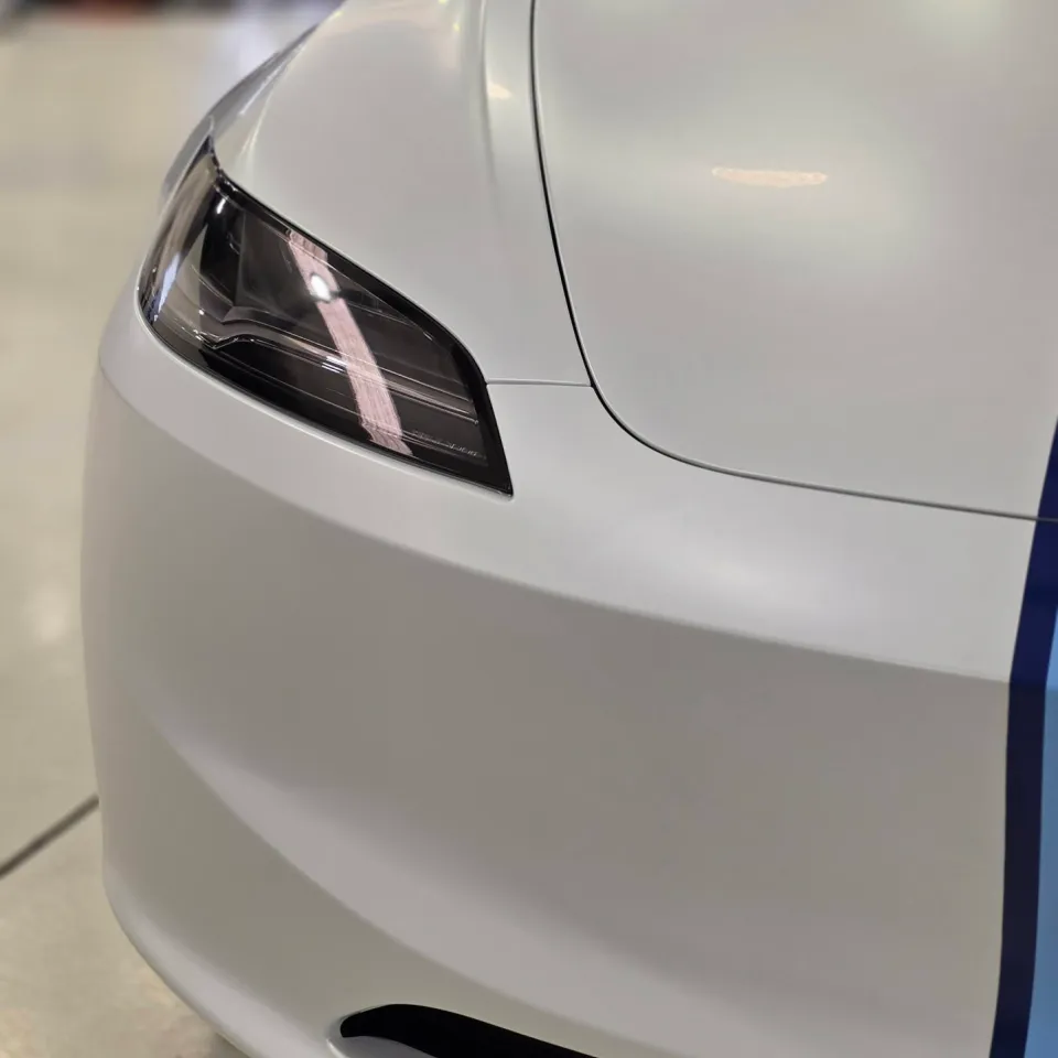 White Tesla front corner showing its slim headlight and bumper