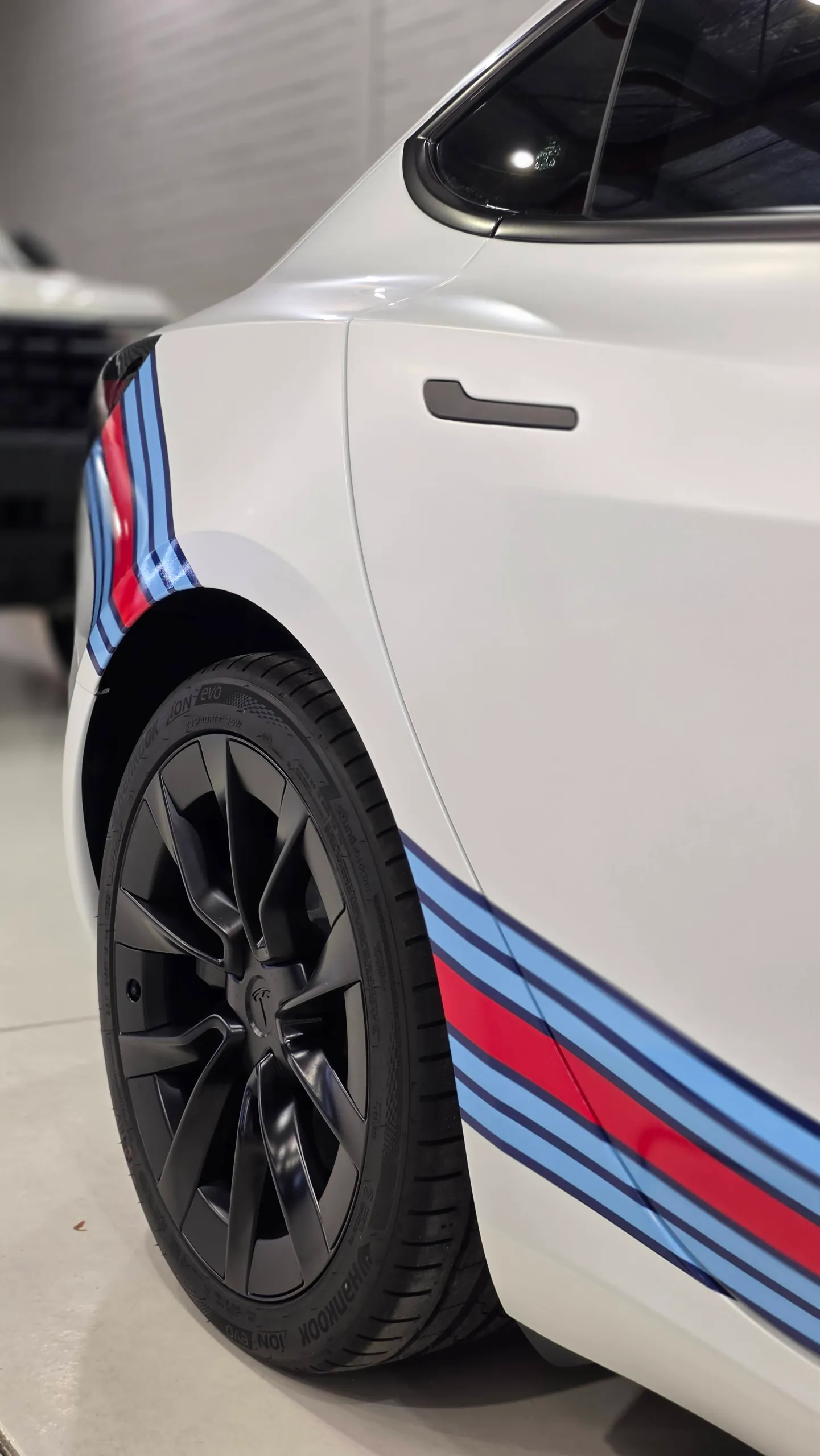 Black Tesla rear wheel beside the red and blue side stripes