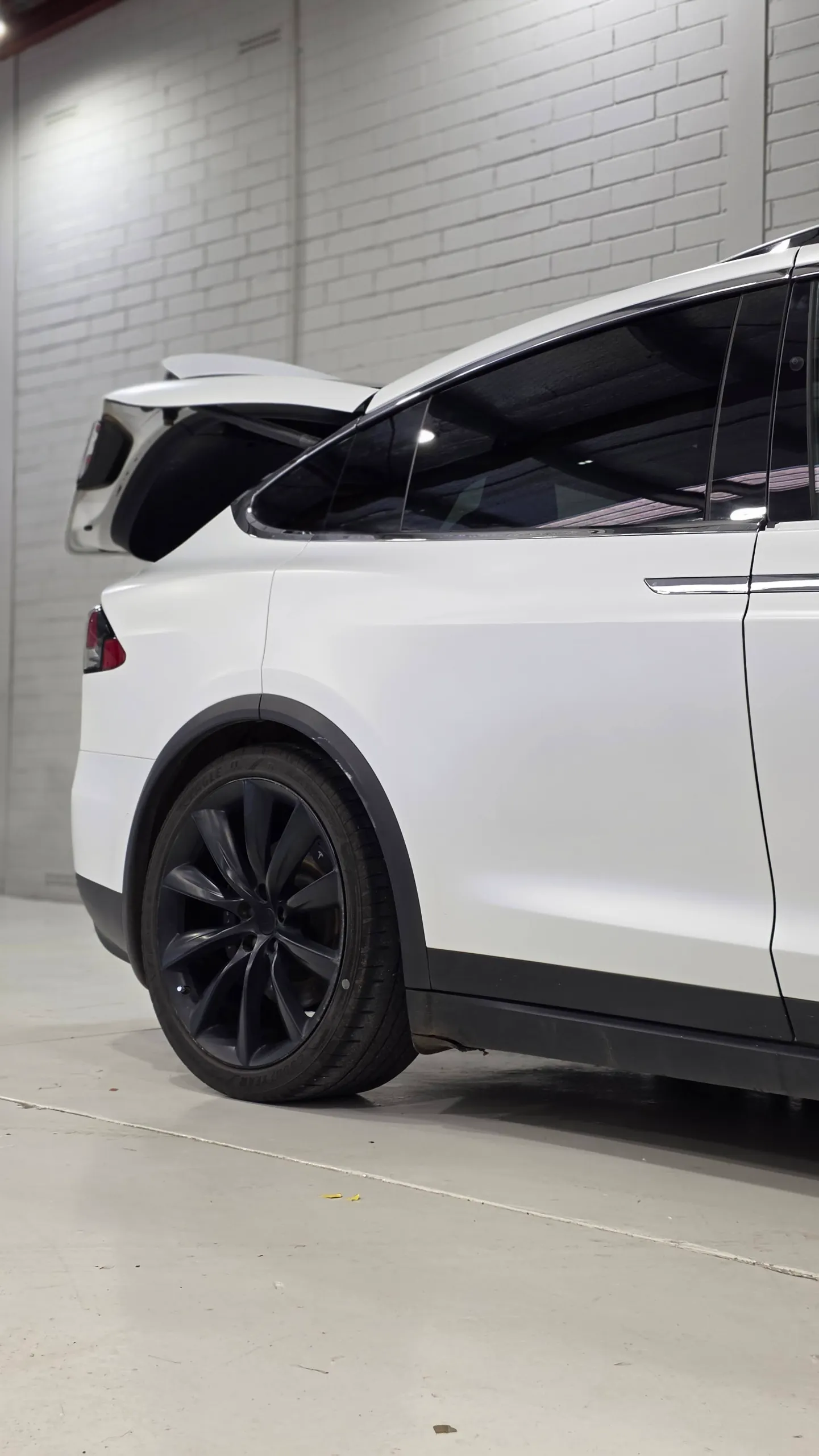 White Tesla Model X rear wheel and side panels with its boot open