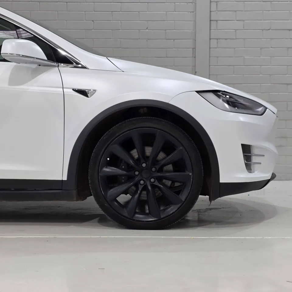 White Tesla Model X front wheel, guard and headlight inside the workshop
