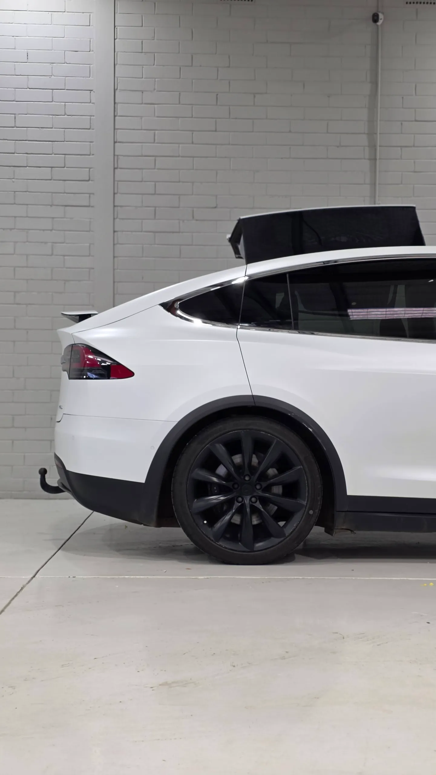 White Tesla Model X rear quarter and black rear wheel with its boot raised