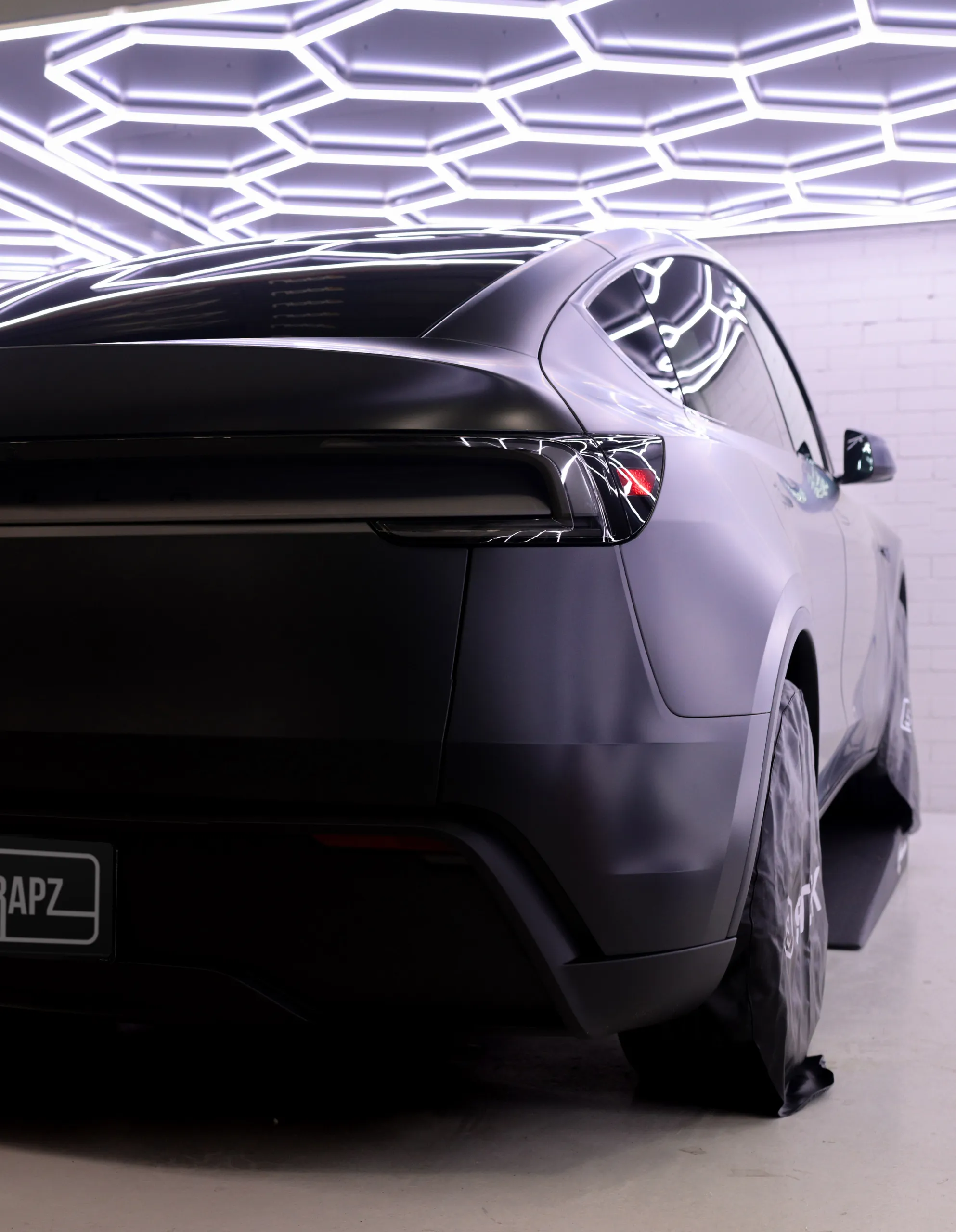 Tesla Model Y satin rear quarter beneath a gloss black roof