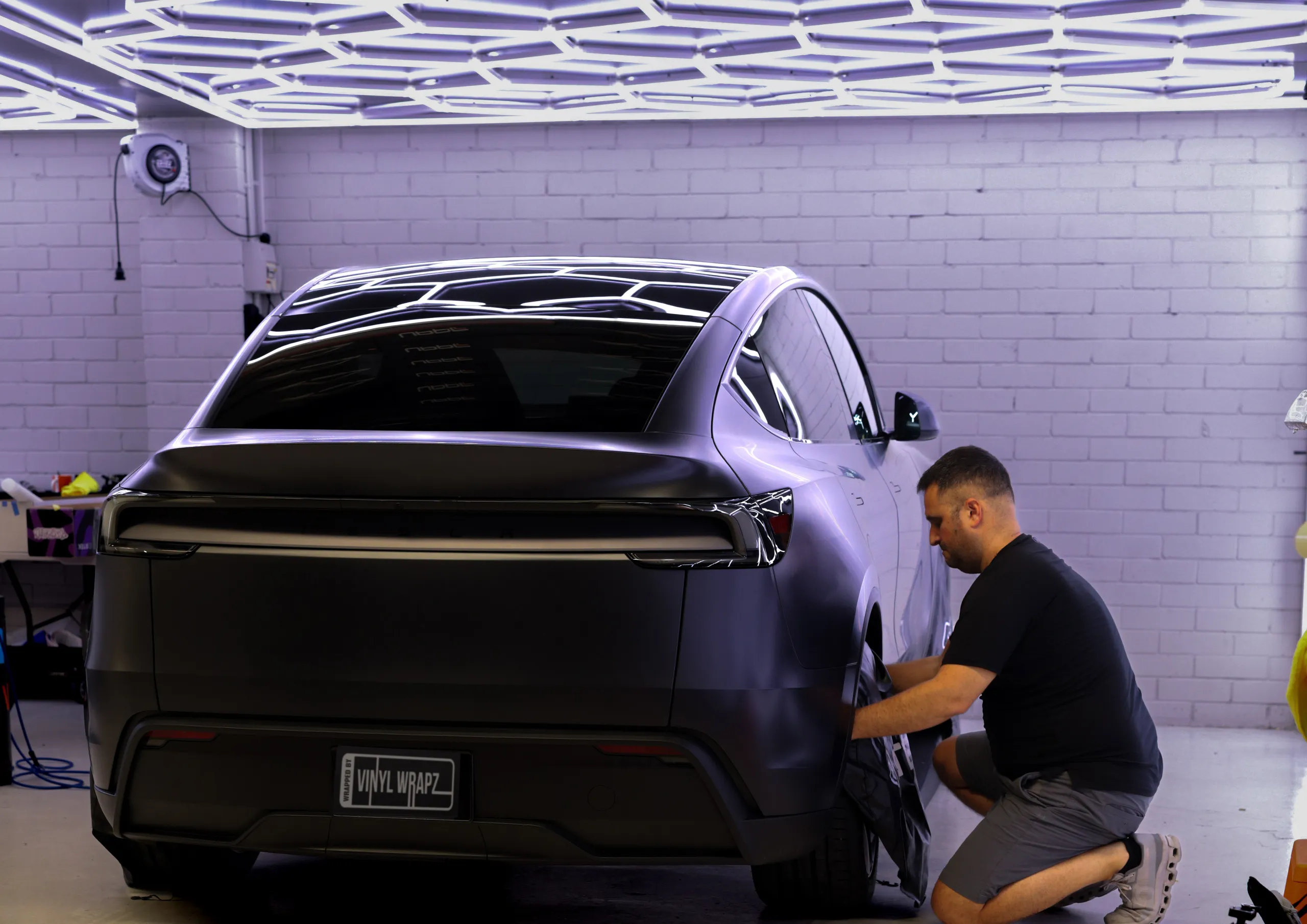 Installer working beside the satin Tesla Model Y rear wheel in the workshop