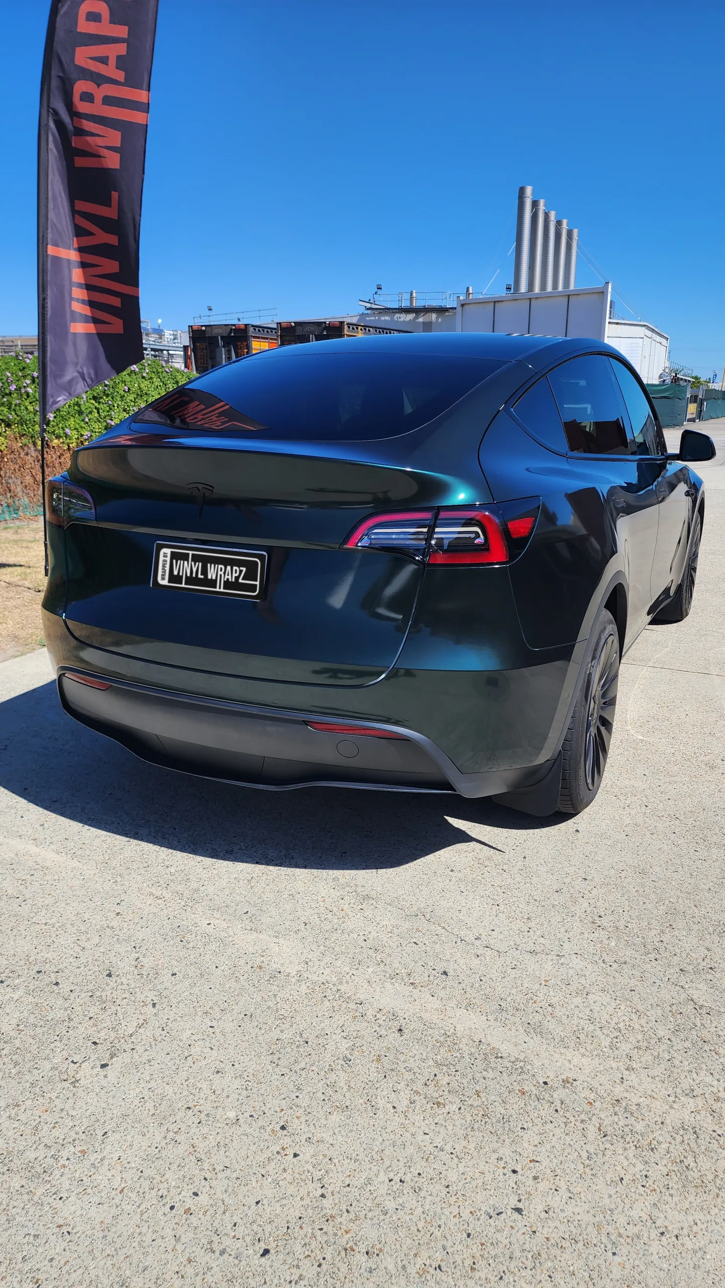 Gloss green and black iridescent Tesla Model Y outside the workshop, rear quarter