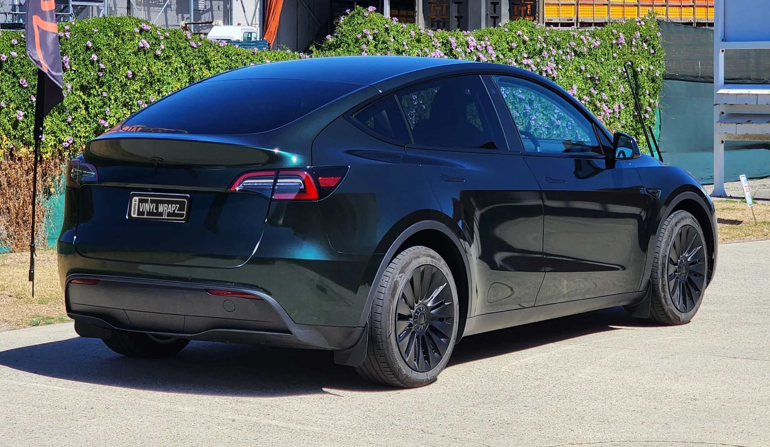 Gloss green and black iridescent Tesla Model Y outside the workshop, rear quarter