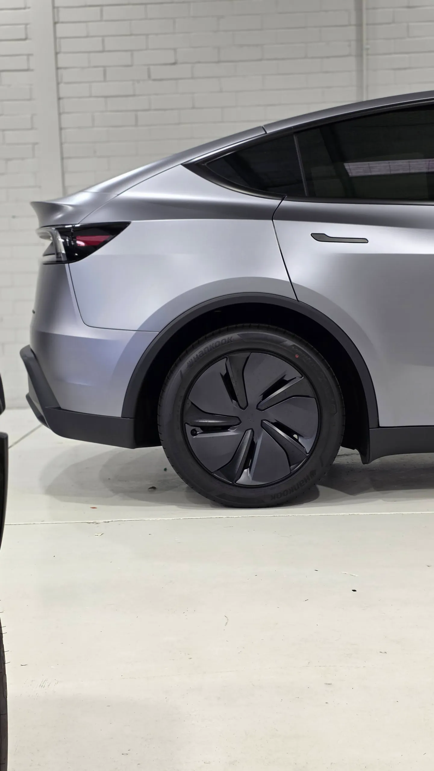 Satin grey Tesla Model Y rear quarter and wheel in the workshop