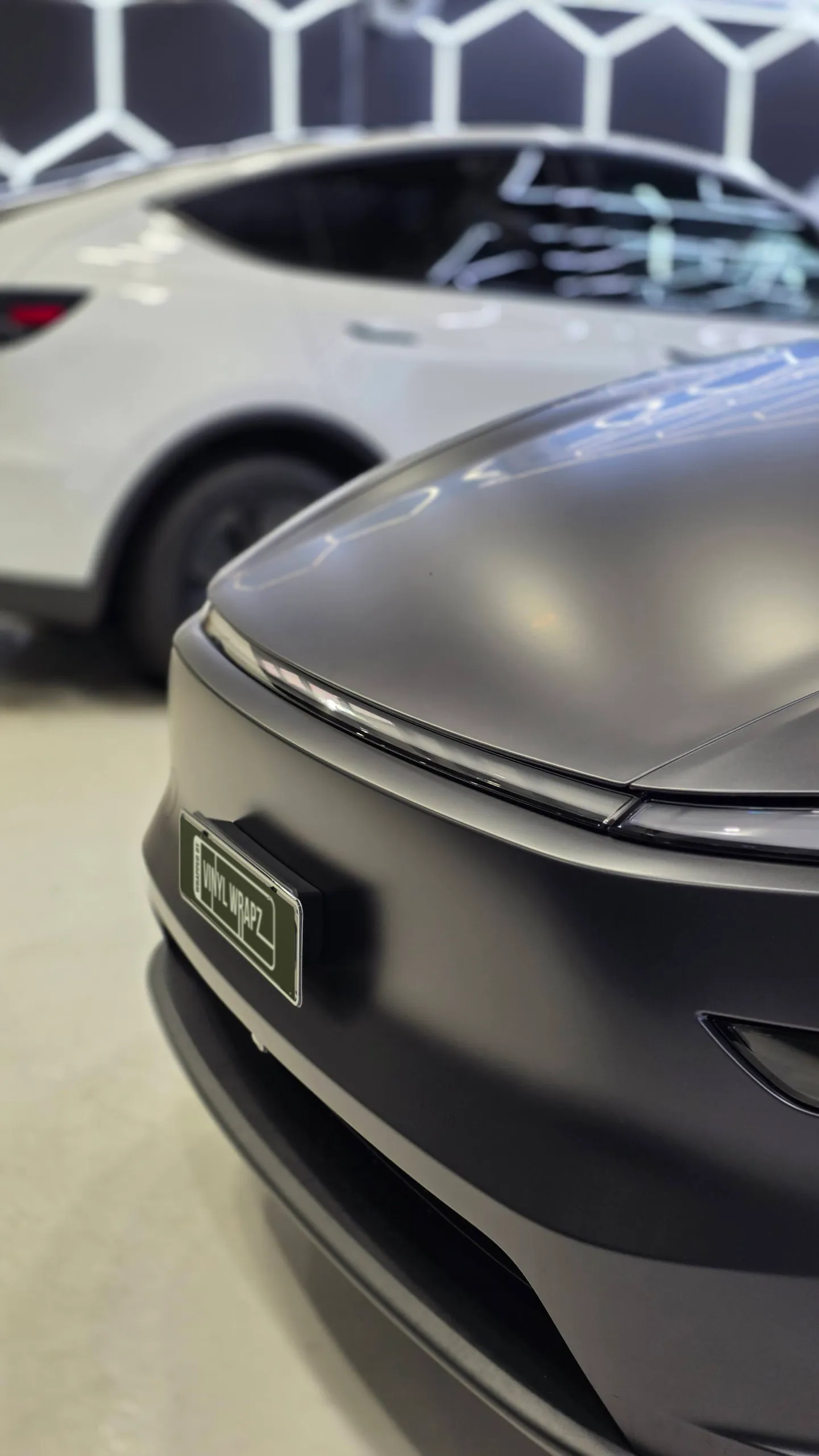 Satin grey Tesla Model Y bonnet and front light bar, with another car behind