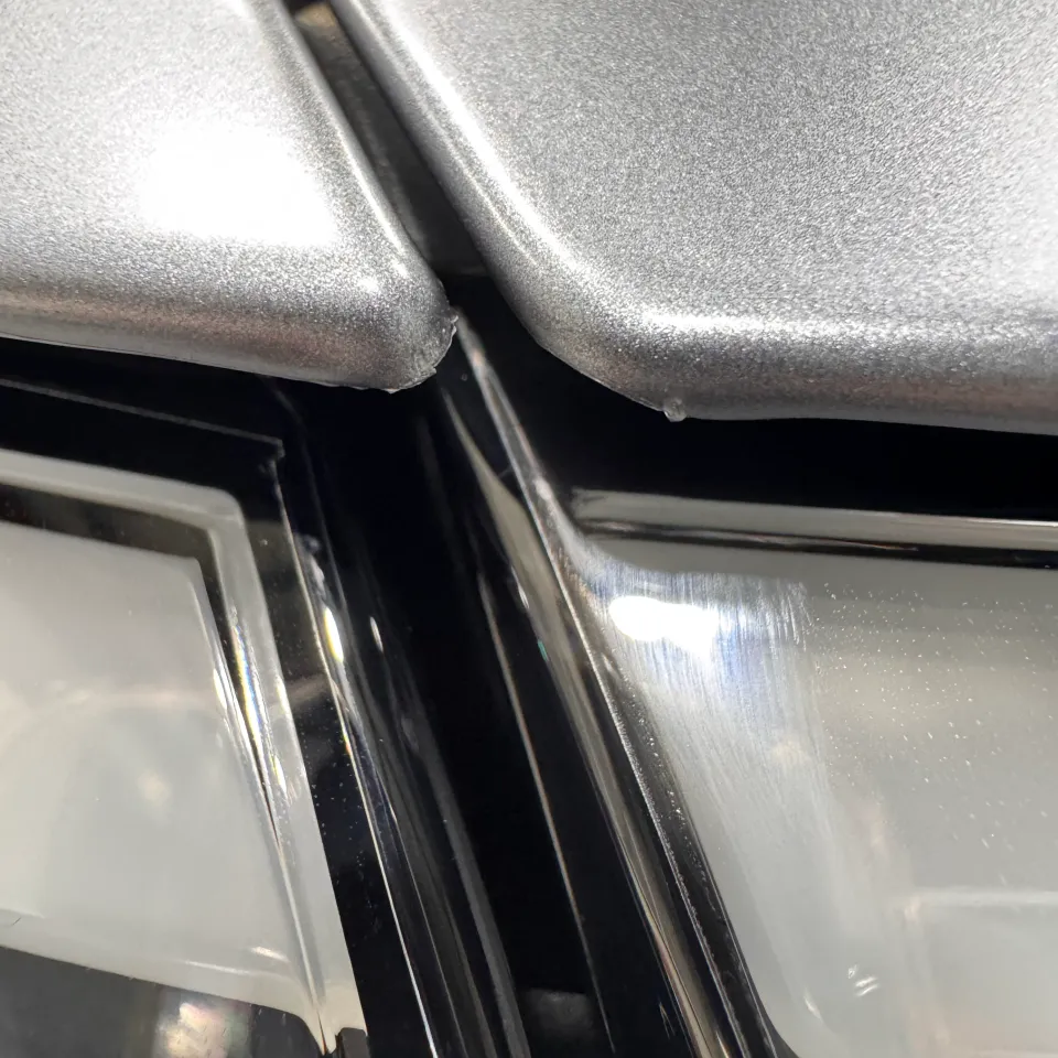 Close-up of film edges where grey Tesla Model Y panels meet above the front light bar