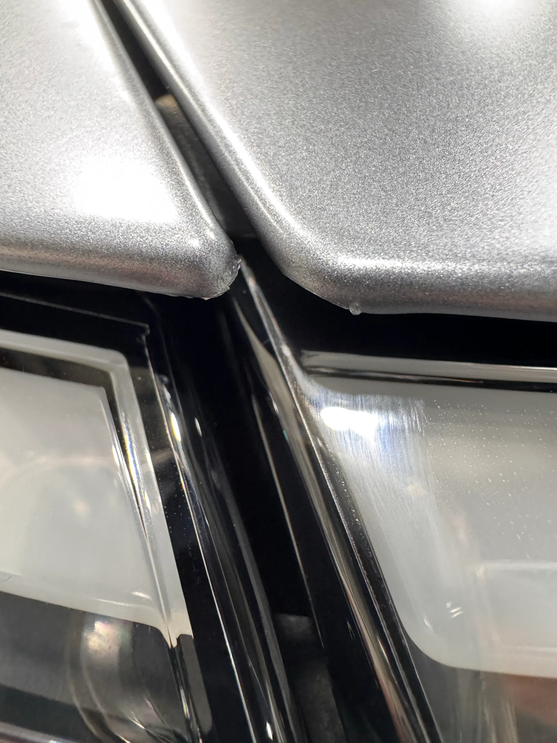 Close-up of film edges where grey Tesla Model Y panels meet above the front light bar