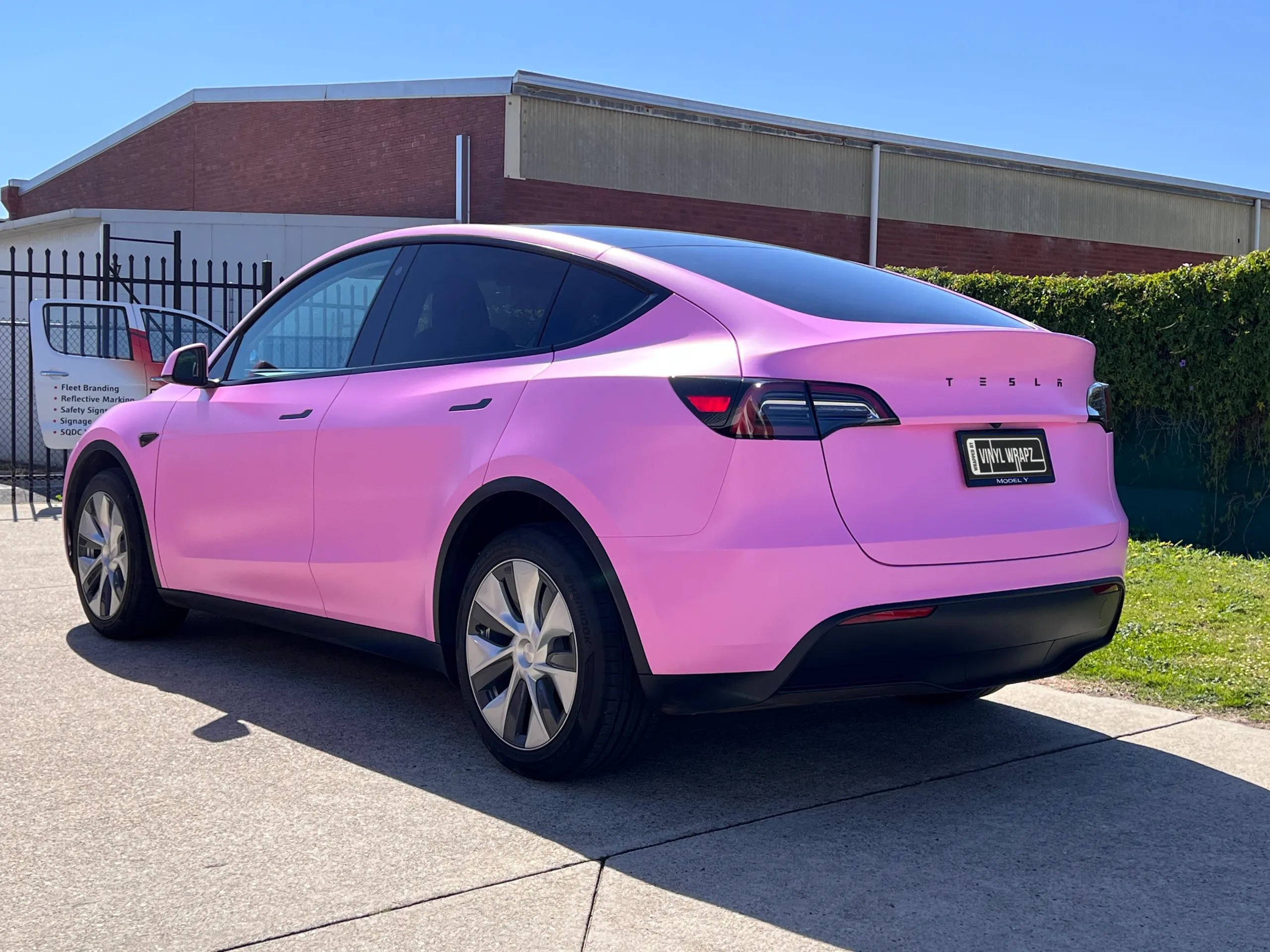 Pink Tesla Model Y viewed from the rear outside the workshop