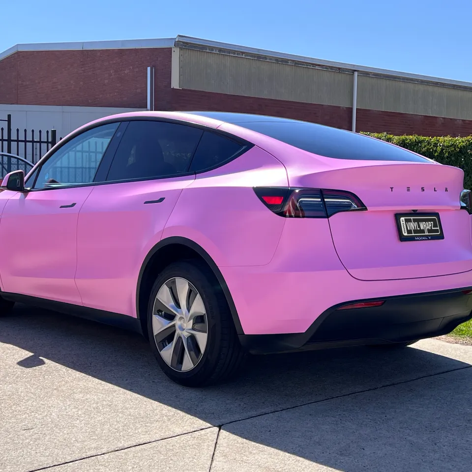 Pink Tesla Model Y viewed from the rear outside the workshop