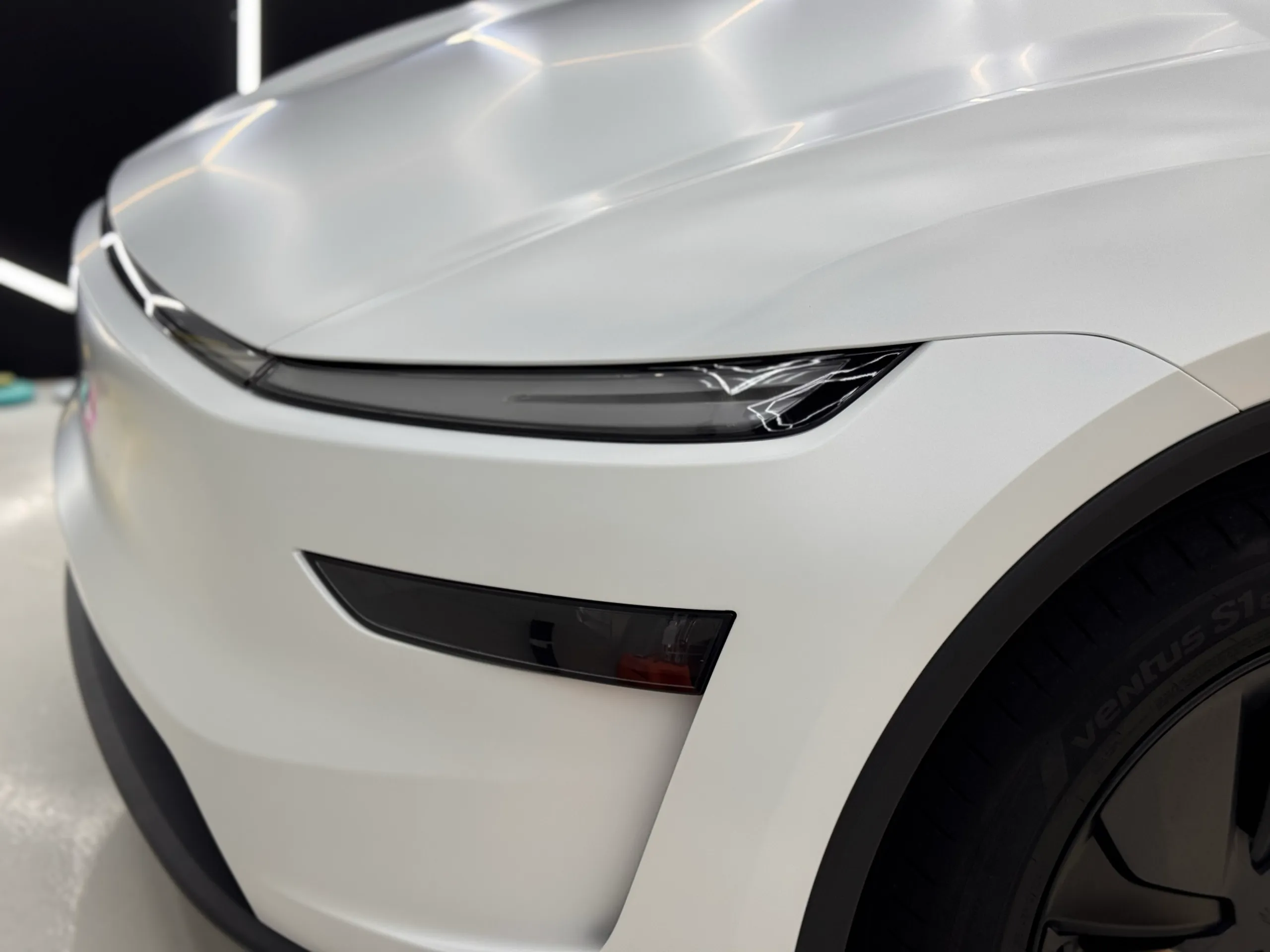 White Tesla Model Y bonnet, light bar and front bumper inside the workshop