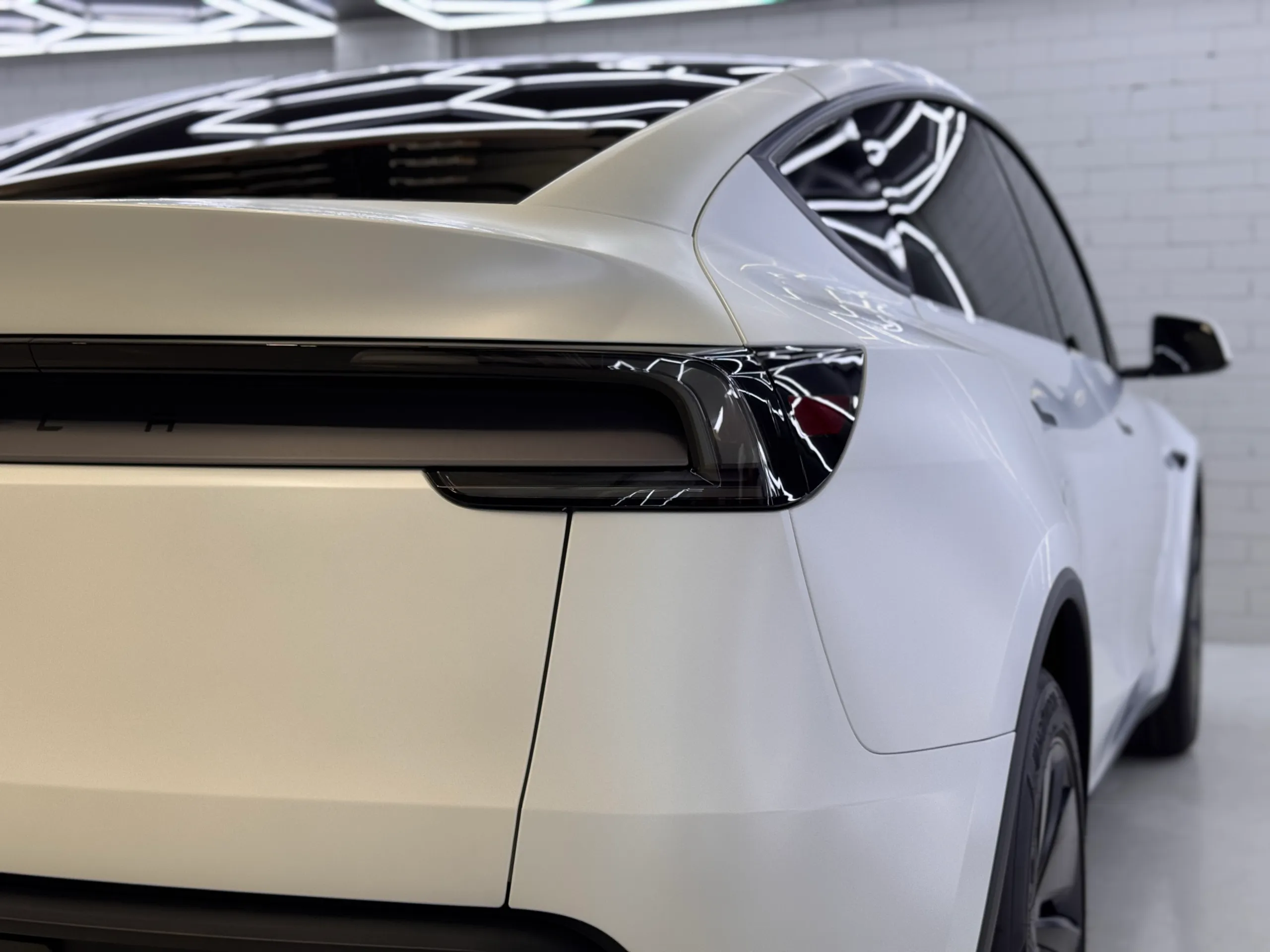 White Tesla Model Y rear quarter, rear glass and dark tail light bar