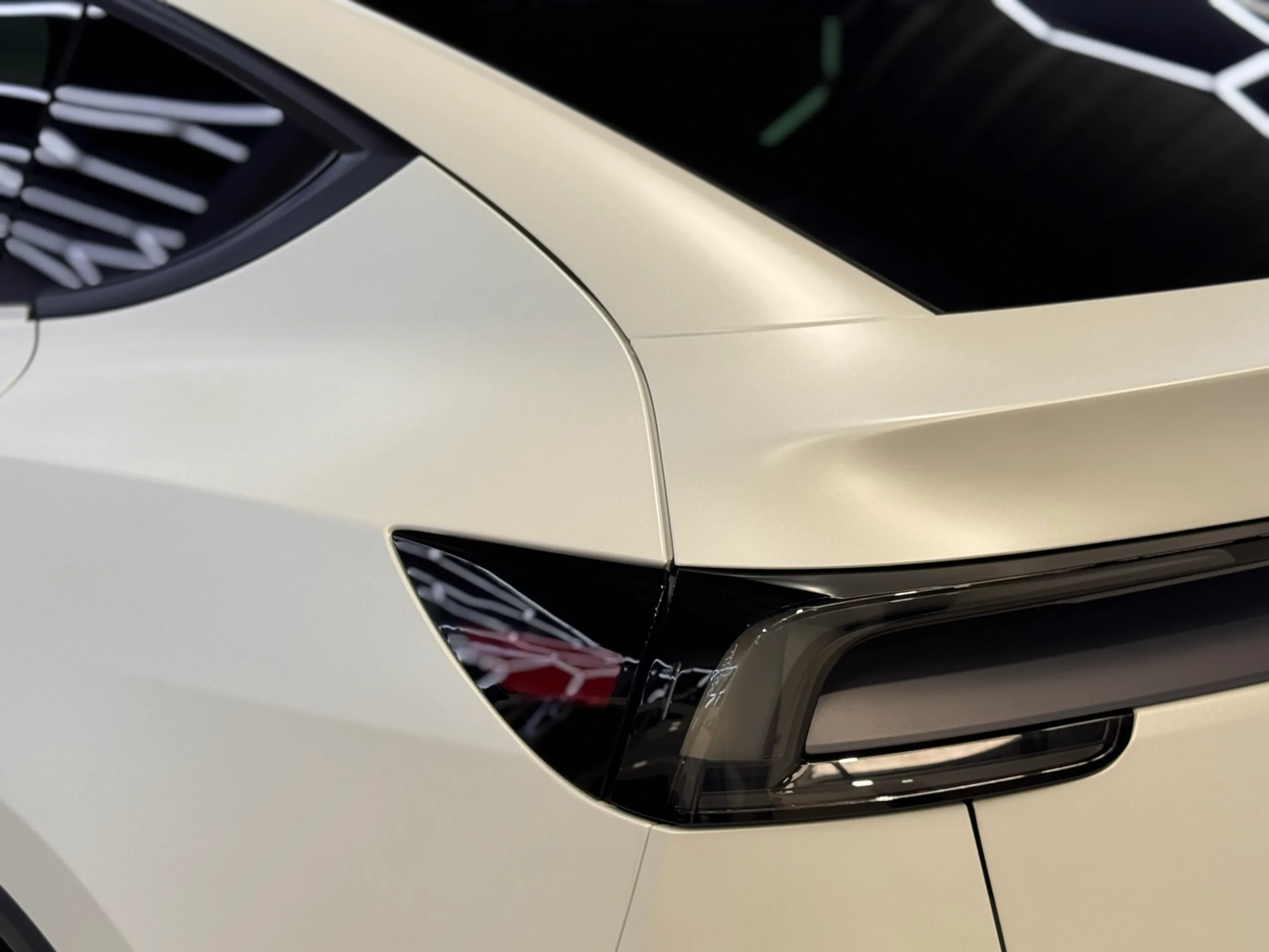 White Tesla Model Y rear pillar and light bar reflecting workshop lights