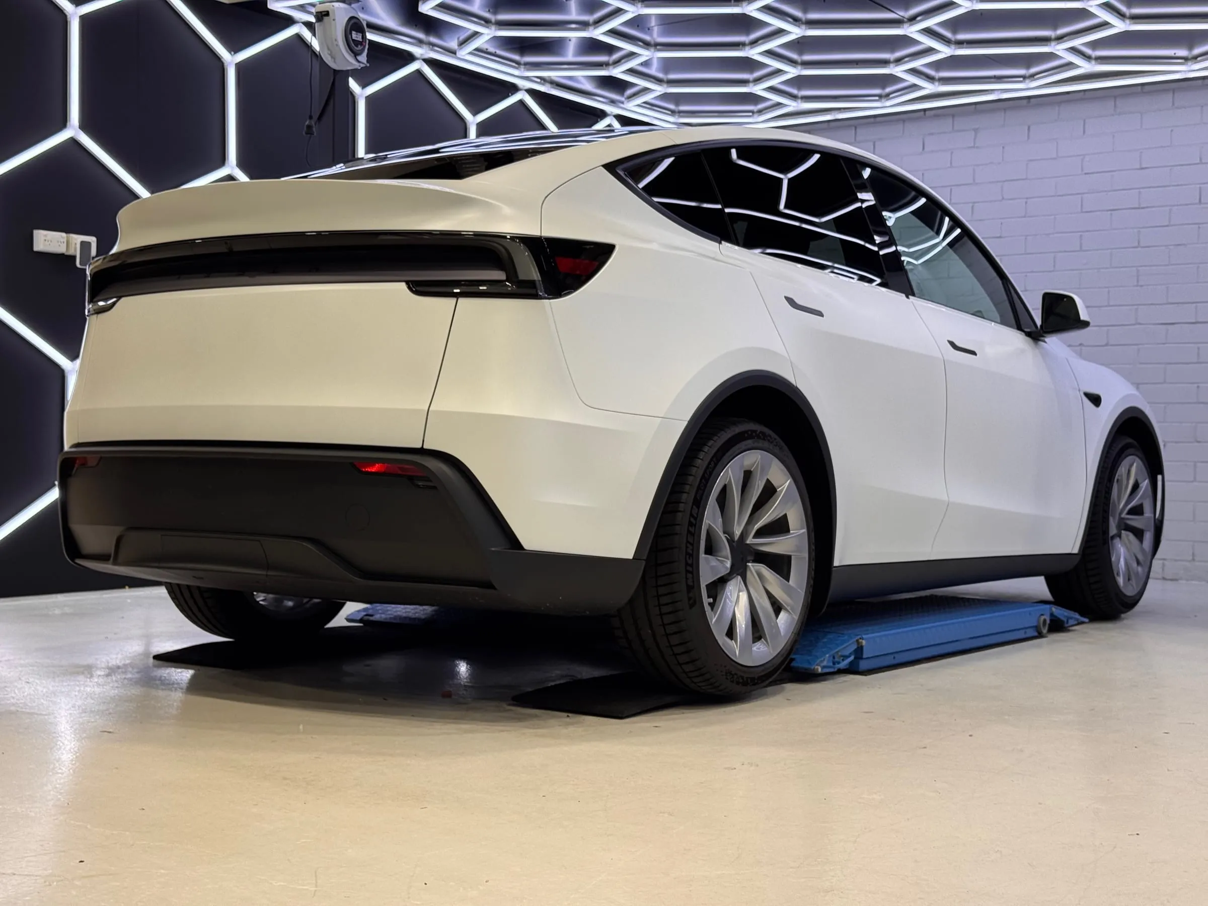 White Tesla Model Y in paint protection film, rear three-quarter view in the Vinyl Wrapz PPF bay, Osborne Park