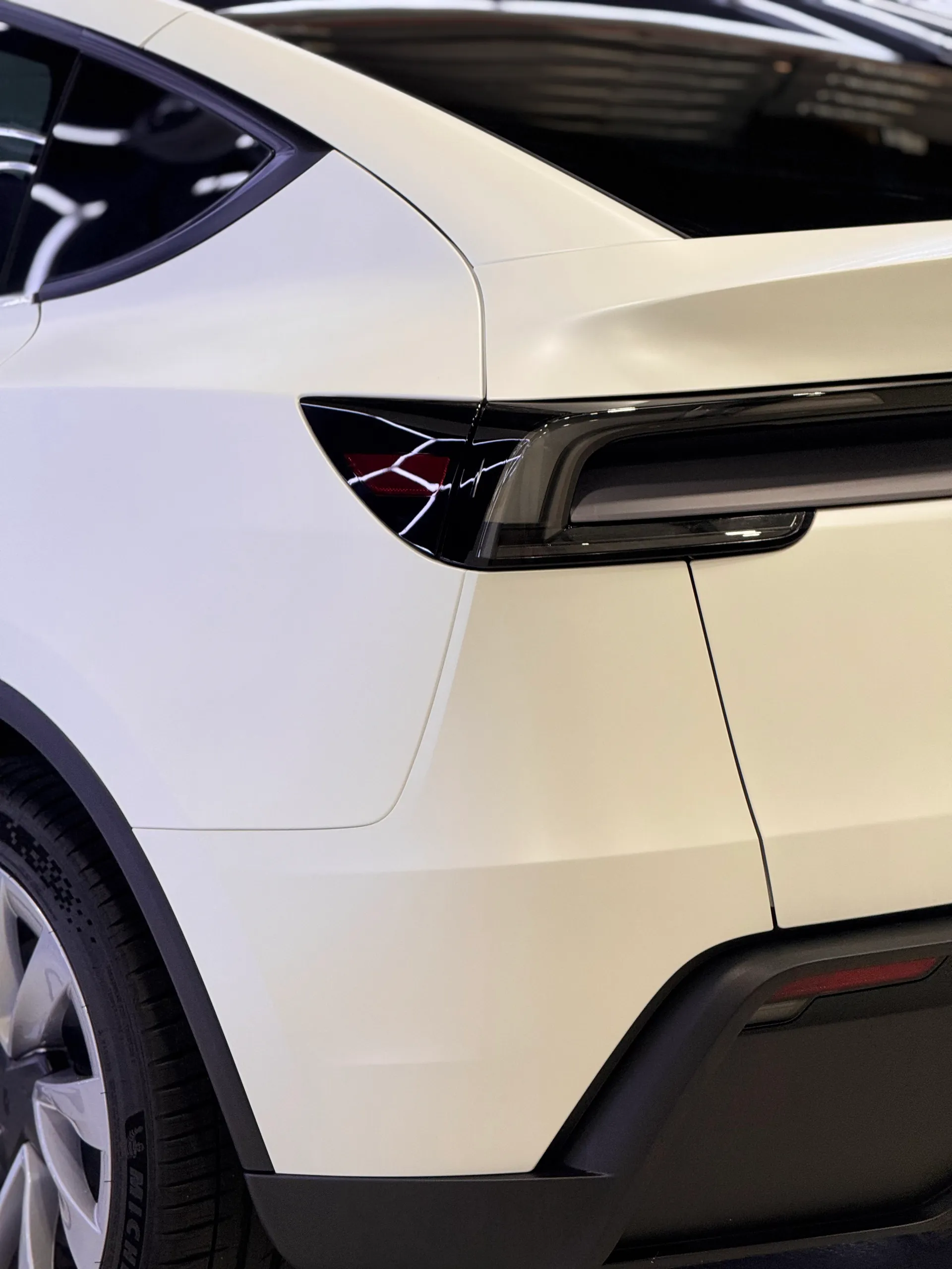 Satin white Tesla Model Y rear quarter and tailgate beside its black rear light bar