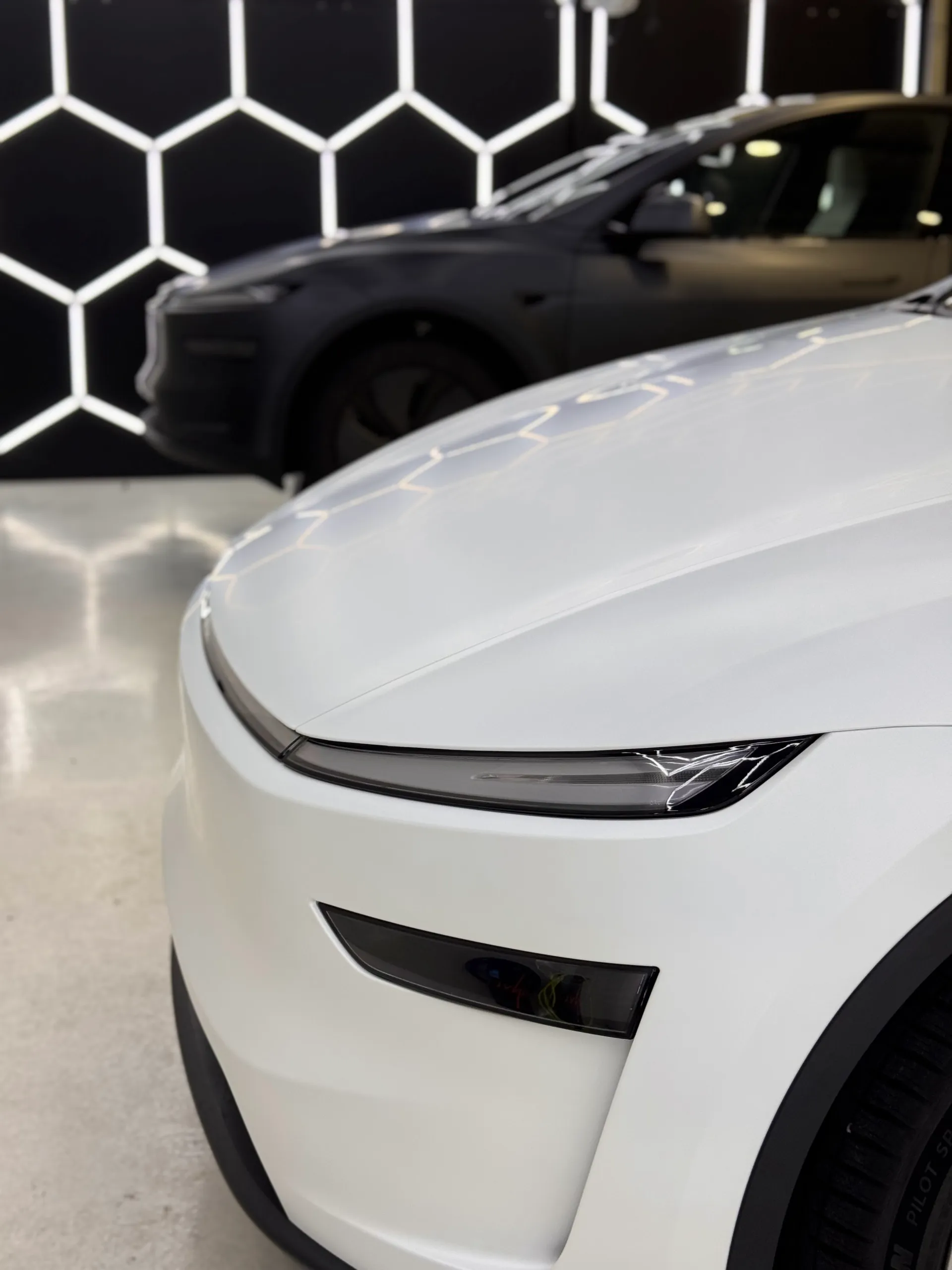 Close-up of the satin white Tesla Model Y front light bar and bumper