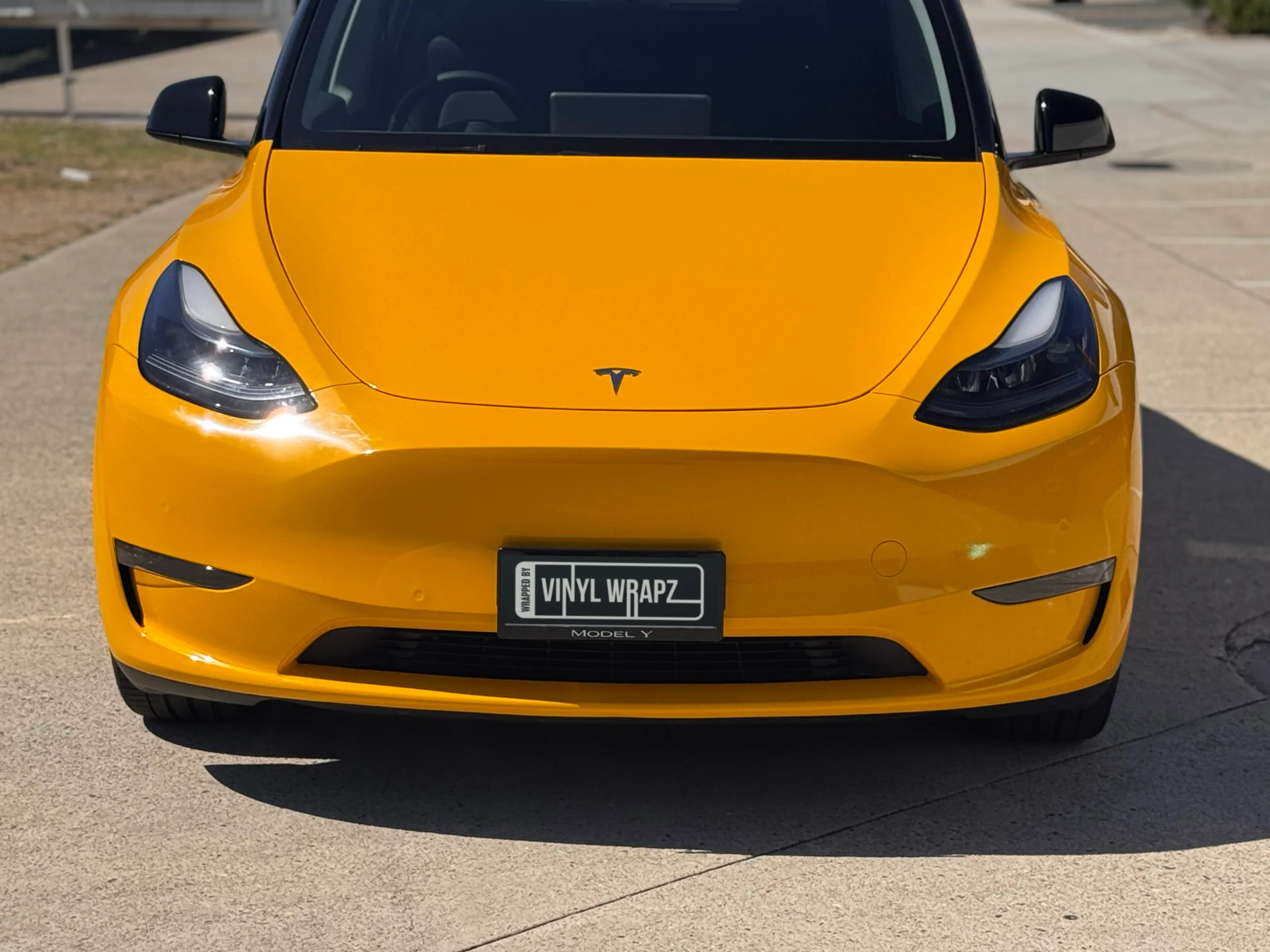 Front view of the gloss yellow Tesla Model Y in sunlight