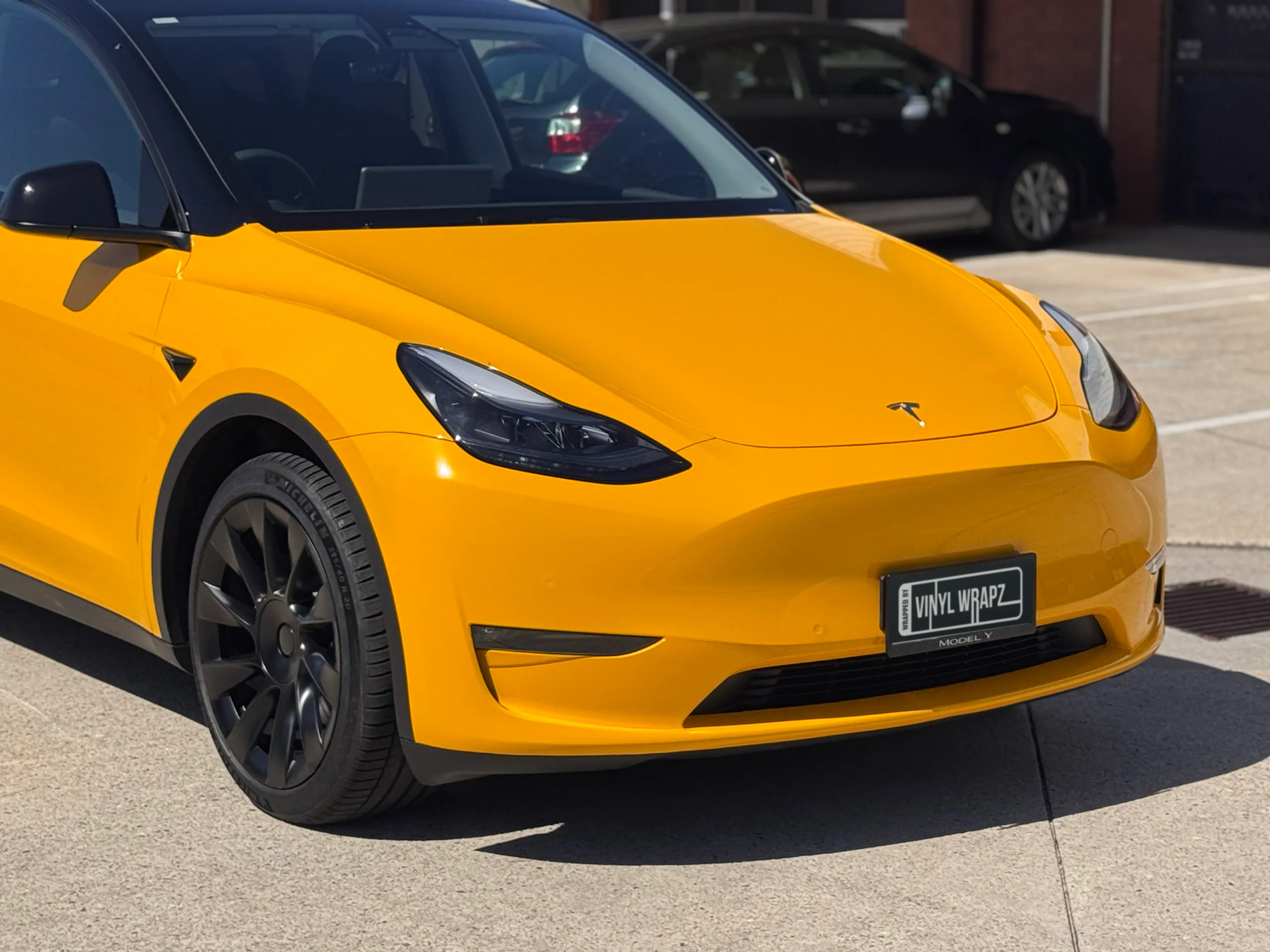 Gloss yellow Tesla Model Y front bumper, bonnet and headlight outdoors