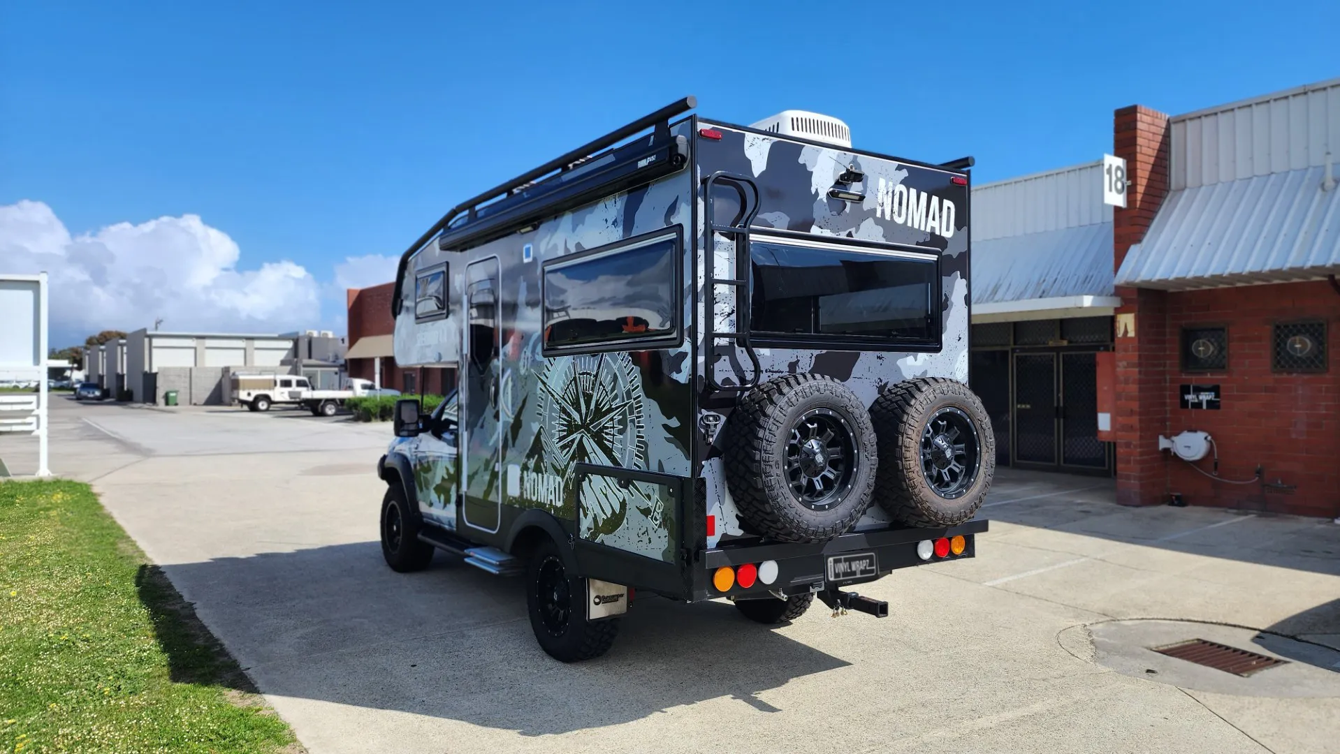 Rear-quarter view of the camouflage Hilux Suncamper with two spare wheels at the back