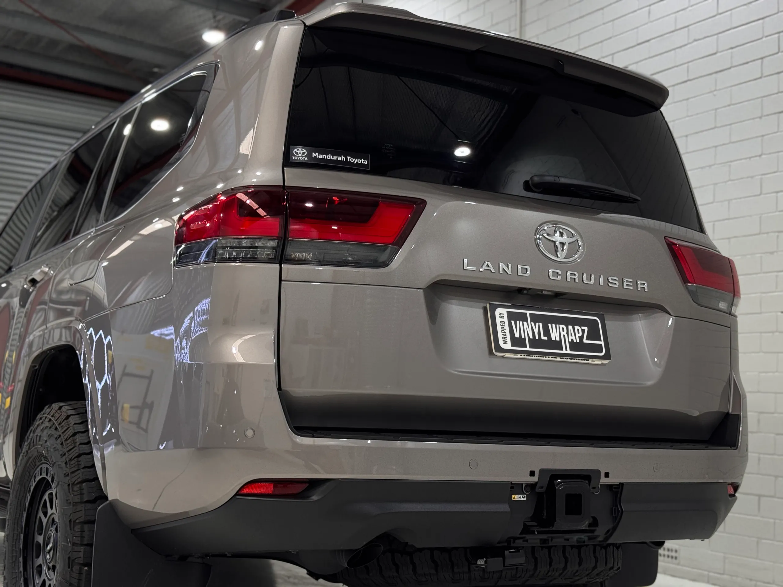 Gloss bronze-grey Toyota LandCruiser 300 rear quarter and tailgate in the workshop