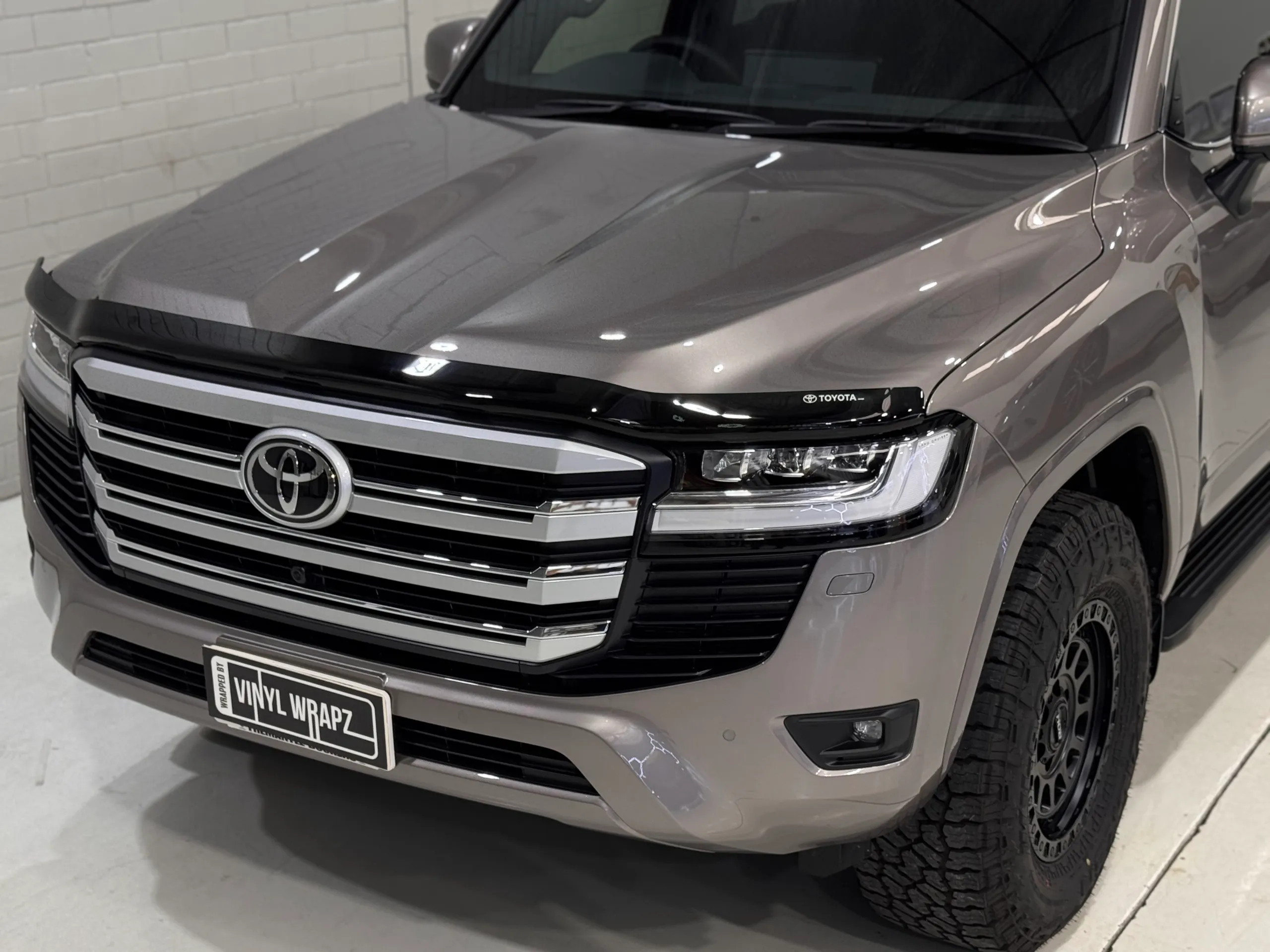 Workshop lights reflected across the gloss LandCruiser 300 bonnet and front guards